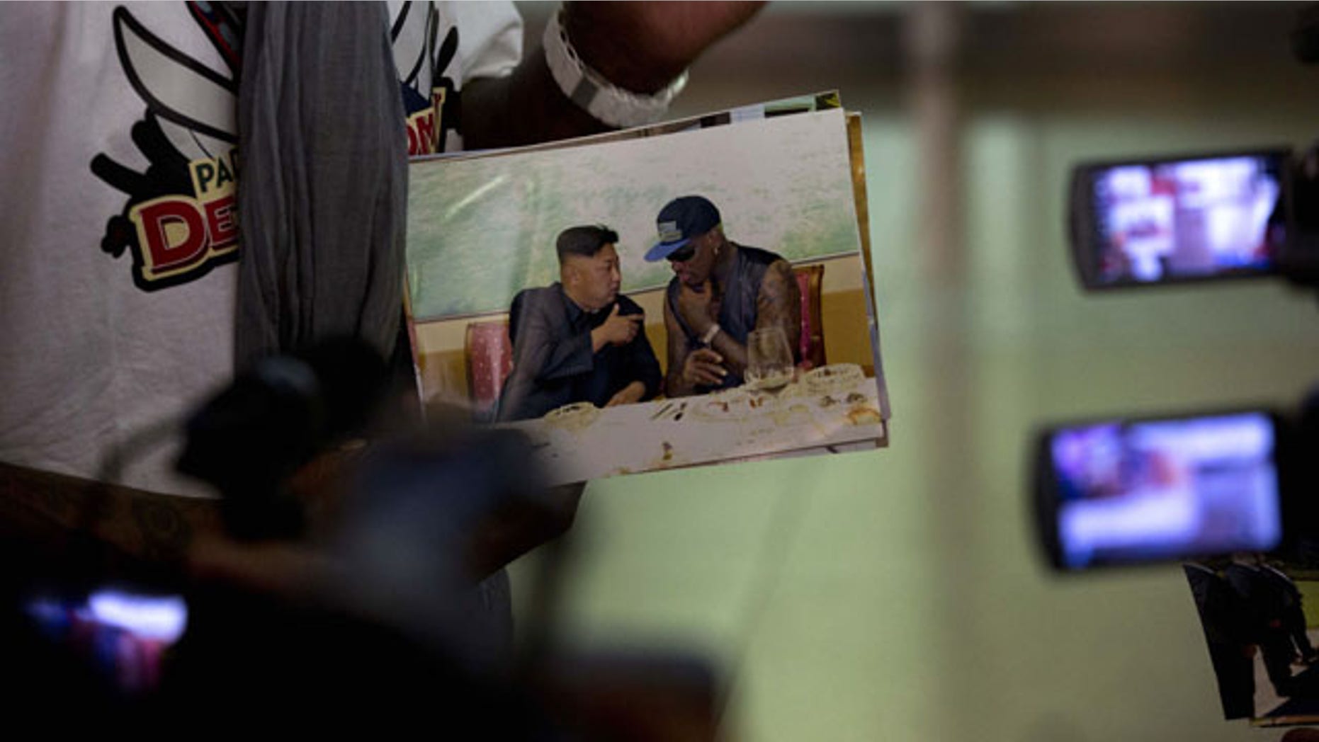 September 7, 2013: Retired NBA star Dennis Rodman, left, shows a photo of him with North Korean leader Kim Jong Un upon arriving at the Beijing capital airport in Beijing, China.