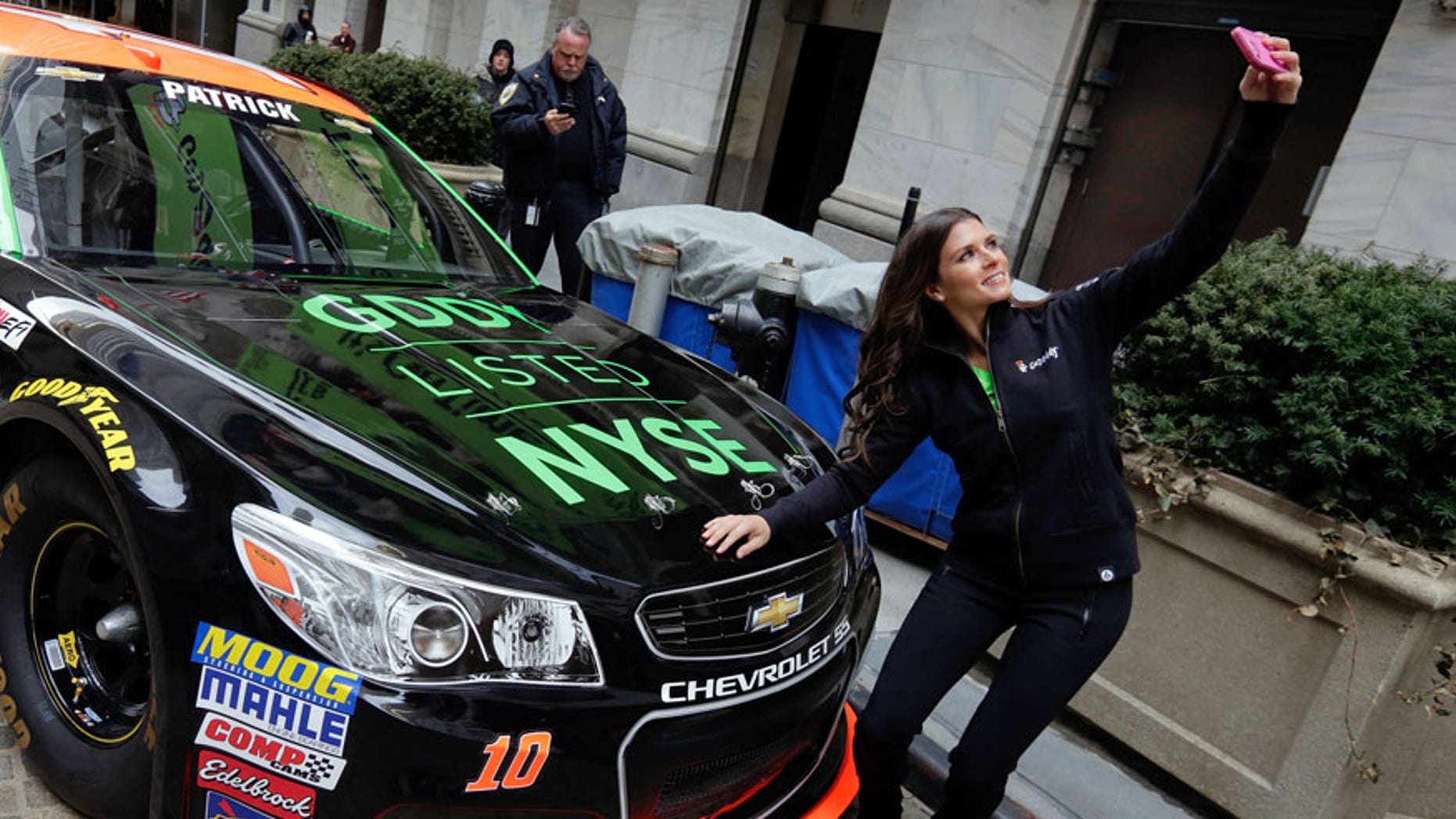 Race car driver Danica Patrick takes a selfie with her car in front of the New York Stock Exchange, before the GoDaddy IPO, Wednesday, April 1, 2015. (AP Photo/Richard Drew)