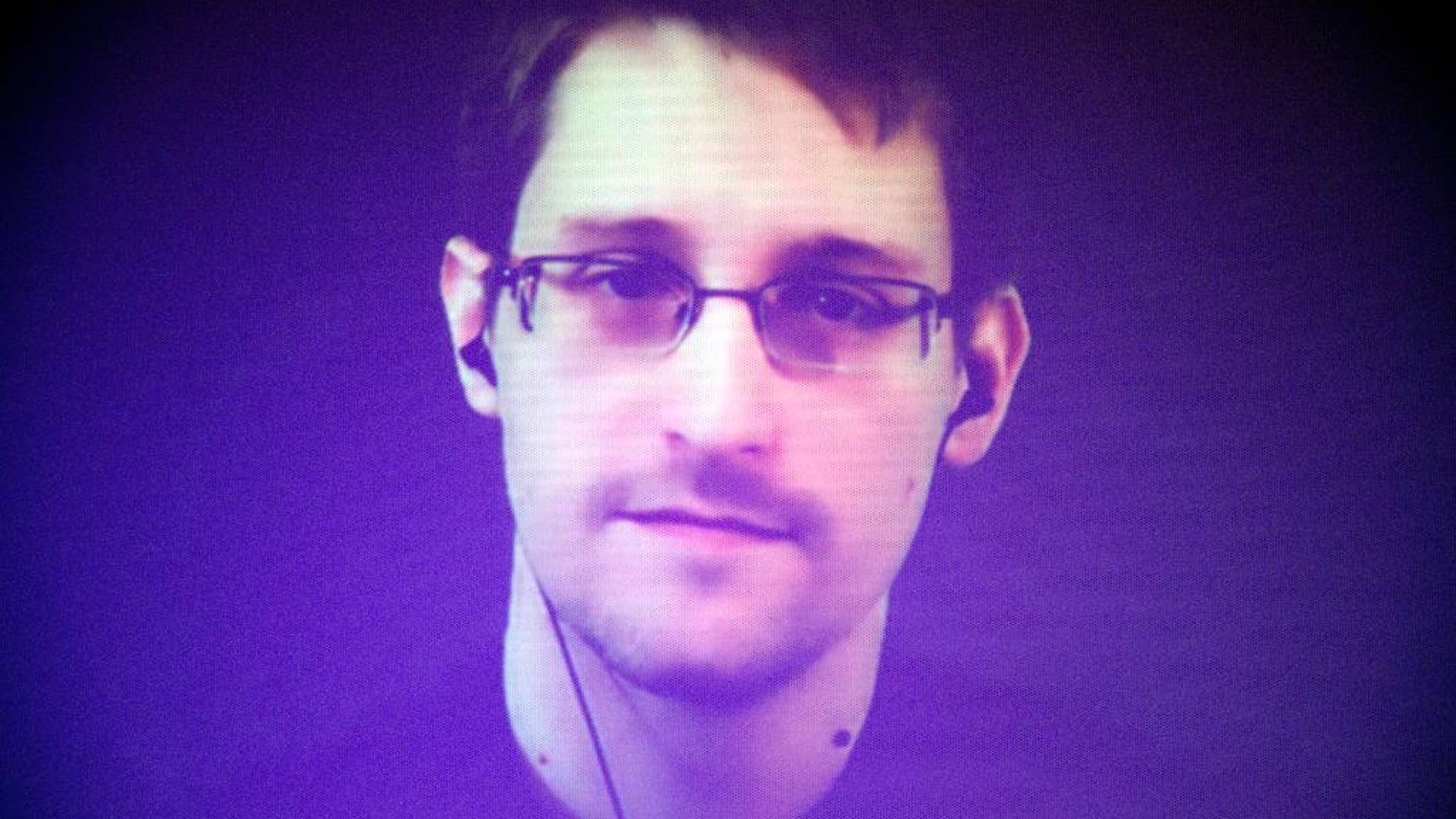 Former U.S. National Security Agency contractor Edward Snowden, who is in Moscow, is seen on a giant screen during a live video conference for an interview as part of Amnesty International's annual Write for Rights campaign at the Gaite Lyrique in Paris, France, Dec. 10, 2014. (AP Photo/Charles Platiau, Pool)