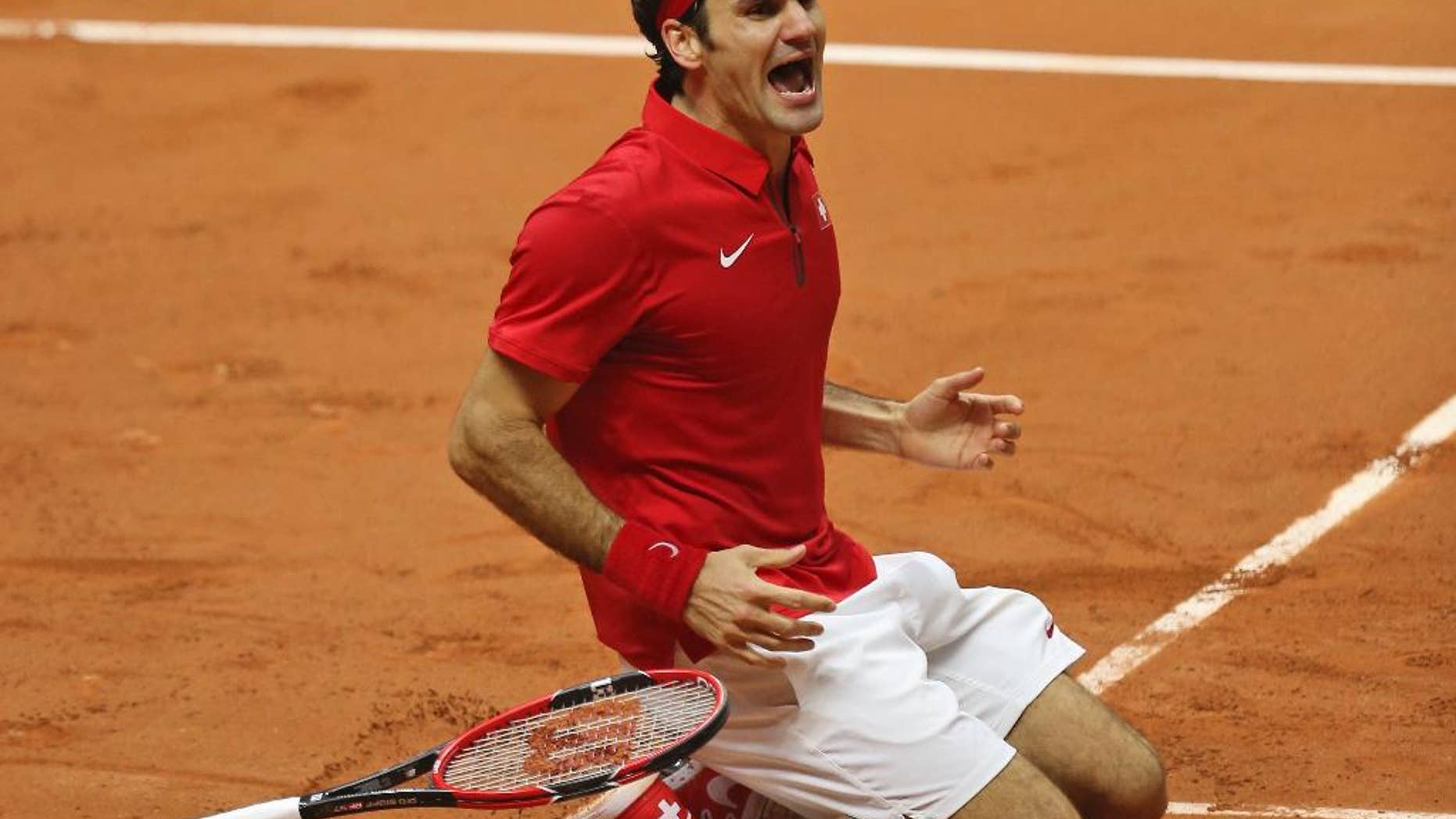 Switzerland's Roger Federer falls to the clay after defeating France's Richard Gasquet and winning the Davis Cup final between France and Switzerland at Stade Pierre Mauroy in Lille, northern France, Sunday, Nov. 23, 2014. (AP Photo/Peter Dejong)