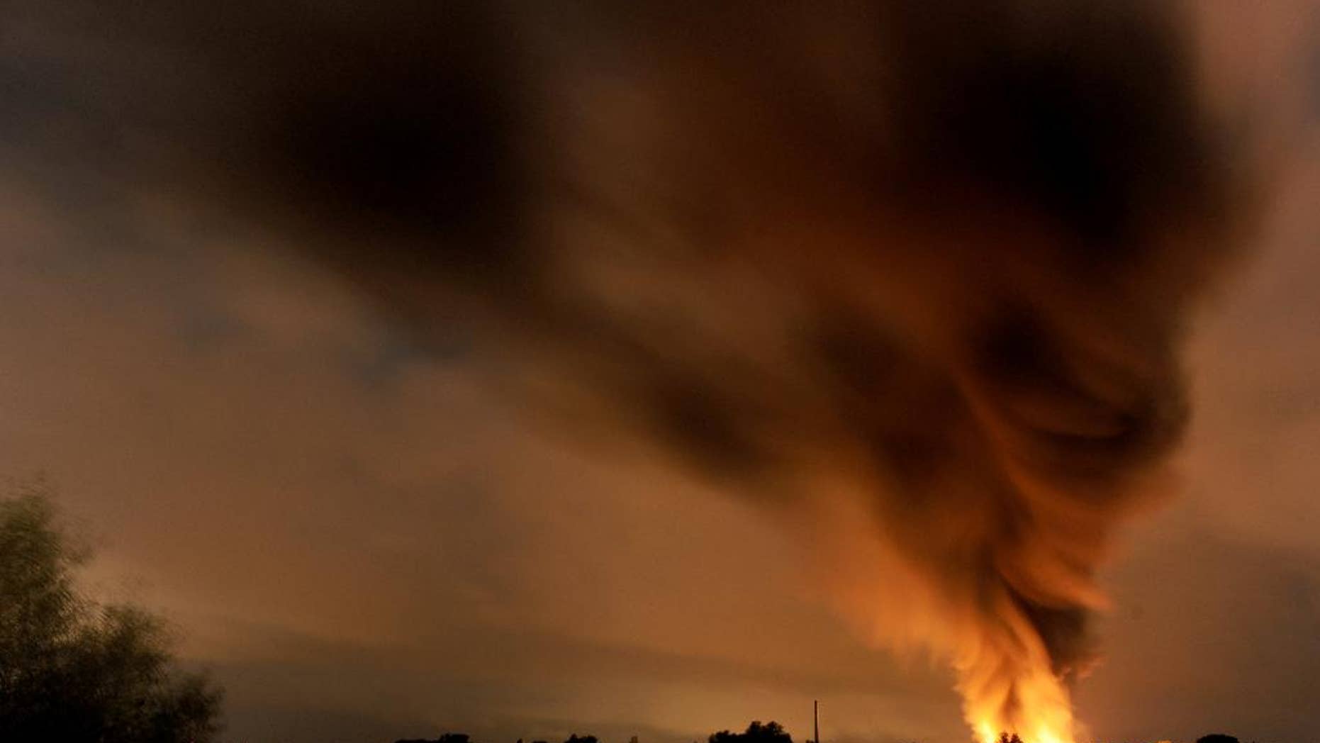 Smoke and flames rise over a chemical waste facility in Ritterhude near Bremen, Tuesday evening, Sept. 9, 2014. Police said that one person was severely burned in the blast Tuesday night and that the explosion damaged a nearby residential area. (AP Photo/dpa, Ingo Wagner)