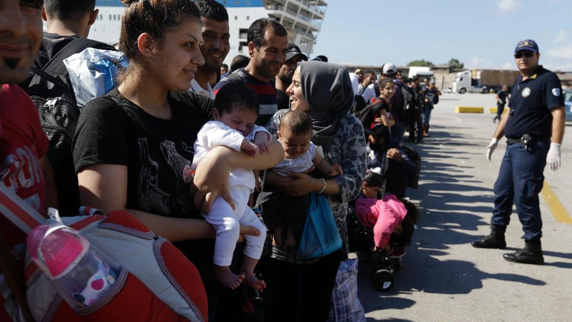 A Syrian mother, left, holds her one-month old daughter as she waits for the bus transporting them to the metro station after their arrival from the Greek island of Lesbos at the Athens' port of Piraeus, Monday, Sept. 28, 2015. The Greek ferry Elefhterios Venizelos is part of special ferry service for refugees and migrants that carries 2,500 paying passengers. More than 250,000 asylum seekers have passed through Greece so far this year. (AP Photo/Thanassis Stavrakis)