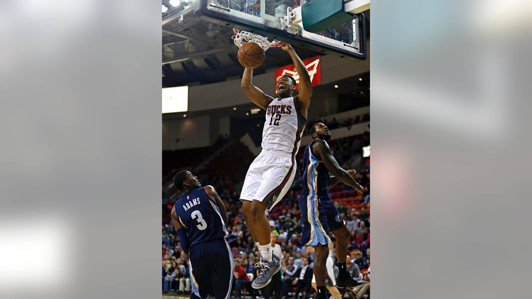 Milwaukee Bucks forward Jabari Parker (12) dunks over Memphis Grizzlies guard Jordan Adams (3) and forward Earl Clark (2) during the second half of an NBA preseason basketball game Wednesday, Oct. 8, 2014, in Green Bay, Wis. Milwaukee won 86-83. (AP Photo/Matt Ludtke)
