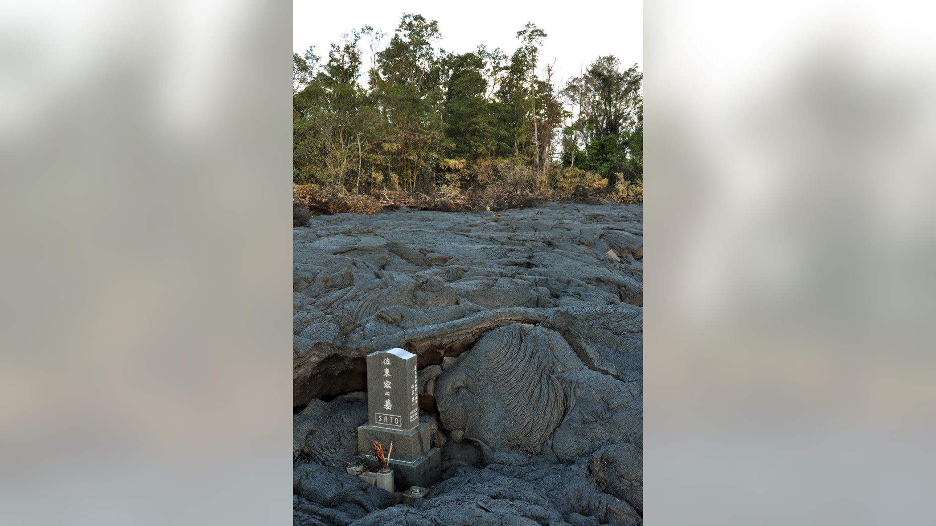 Oct. 28, 2014: This photo provided by the U.S. Geological Survey with the permission of the Sato family shows the Sato headstone still standing in a sea of black lava in a cemetery in Pahoa, Hawaii. (AP/U.S. Geological Survey)