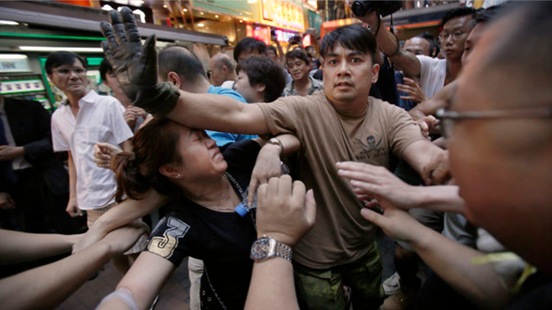October 4, 2014: A woman is protected from the crowd by pro-democracy student protesters after a scuffle with local residents in Mong Kok, Hong Kong. Friction between pro-democracy protesters and opponents of their weeklong occupation of major Hong Kong streets persisted Saturday as police denied they had any connection to criminal gangs suspected of inciting attacks on largely peaceful demonstrators. (AP Photo/Wally Santana)