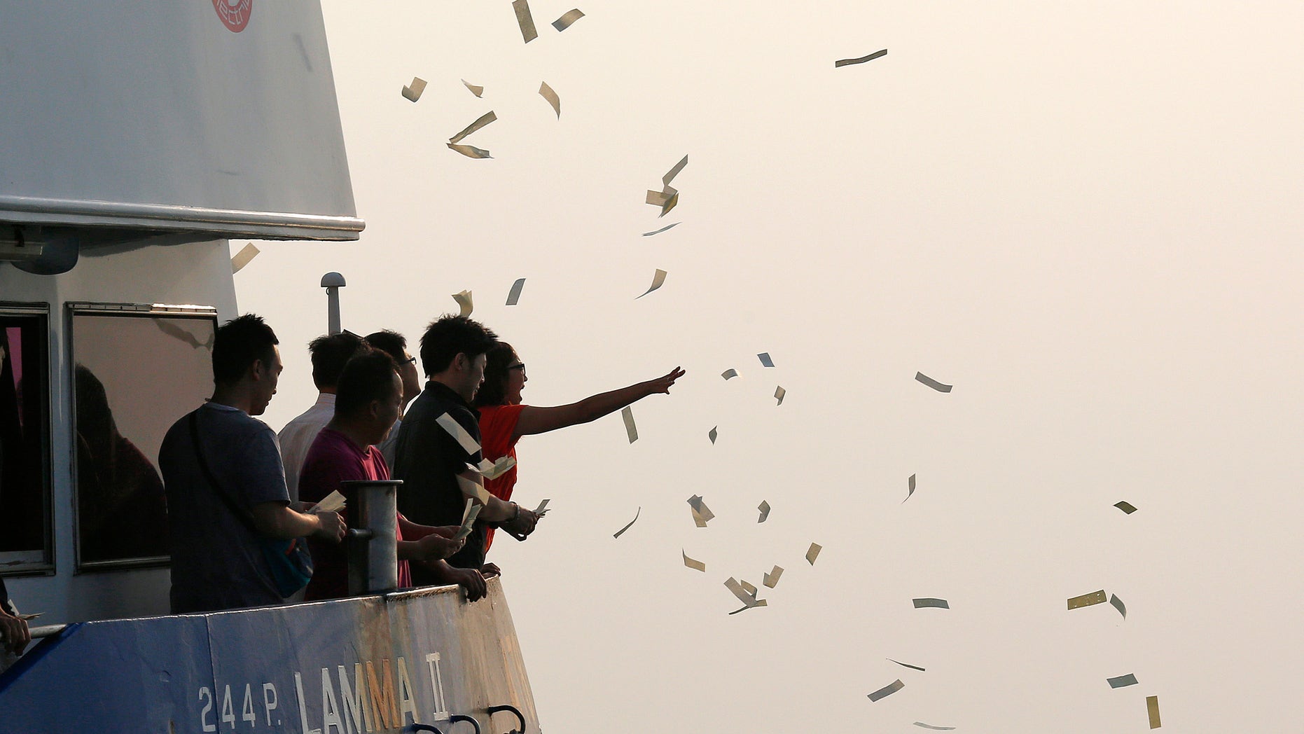 Oct. 2, 2012: Relatives of the victims throw paper money as they pay tribute to the ill-fated people aboard a boat that sank Monday night near Lamma Island, off the southwestern coast of Hong Kong Island.