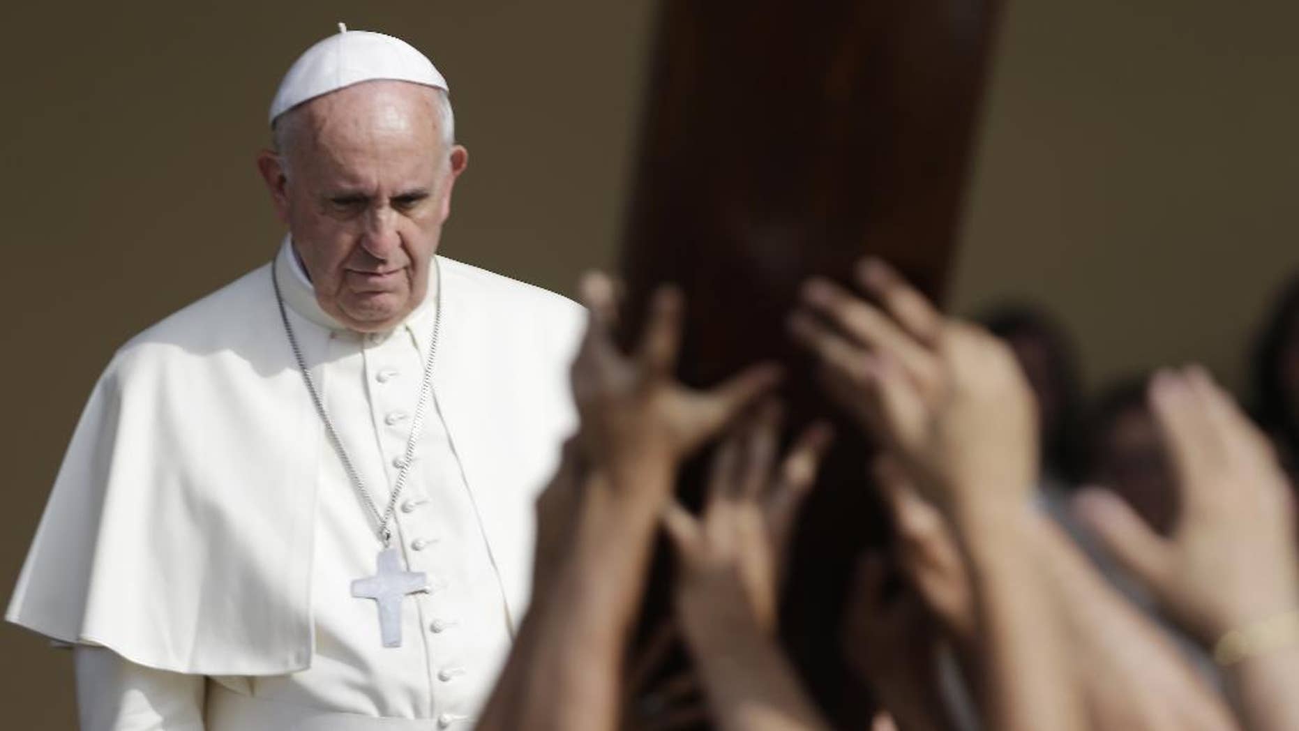 Pope Francis waits for a group of young people carrying a wooden cross during a meeting with the youths, in Turin, Italy, Sunday, June 21, 2015. Pope Francis earlier prayed in front of the Holy Shroud, the 14 foot-long linen revered by some as the burial cloth of Jesus, on display at the Cathedral of Turin.