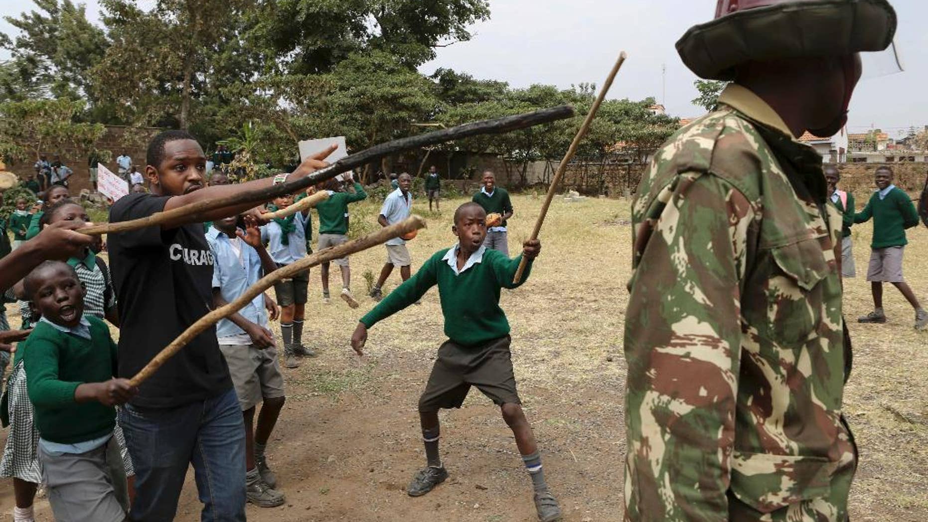 Kenyan school pupils and activists challenge riot police during a protest against the removal of their school's playground, at the Langata Road Primary School, in Nairobi, Kenya Monday, Jan. 19, 2015. Kenyan police tear-gassed schoolchildren demonstrating against the removal of their school's playground, the land of which has been allegedly grabbed by a powerful politician, according to a Kenyan human rights activist. (AP Photo/Brian Inganga)