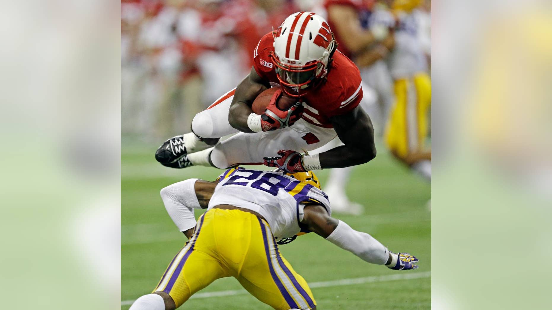 Wisconsin's Melvin Gordon leaps over LSU safety Jalen Mills (28) for a 14-yard touchdown run during the first half of an NCAA college football game Saturday, Aug. 30, 2014, in Houston. (AP Photo/David J. Phillip)