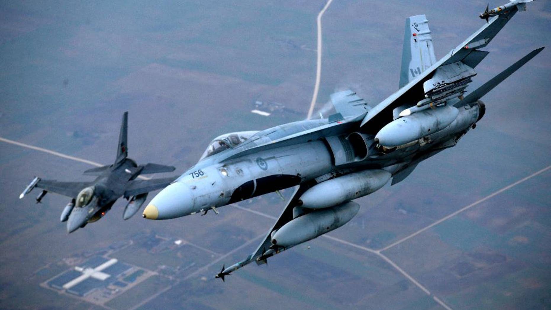 A Portuguese military fighter jet, left, and a Canadian military fighter jet participating in NATO's Baltic Air Policing Mission operate in Lithuanian airspace, Thursday, Nov. 20, 2014. NATO, which has 16 fighter jets in the region monitoring Baltic airspace, said it regularly launches jets to identify "unknown or potentially hostile aircraft" in the proximity of national airspace. (AP Photo/Mindaugas Kulbis)