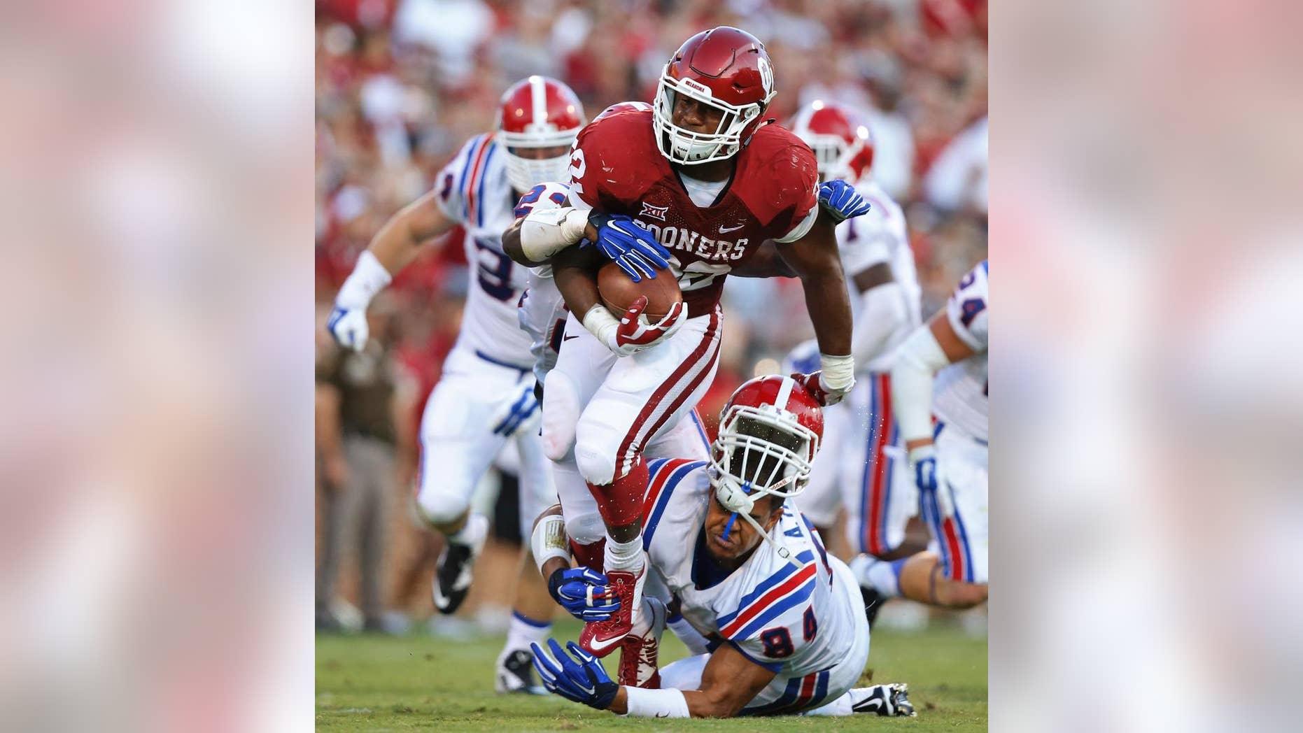 Oklahoma running back Samaje Perine (32) escapes a tackle attempt by Louisiana Tech defensive lineman Andre Taylor during the second quarter of an NCAA college football game in Norman, Okla., Saturday, Aug. 30, 2014. (AP Photo/Sue Ogrocki)