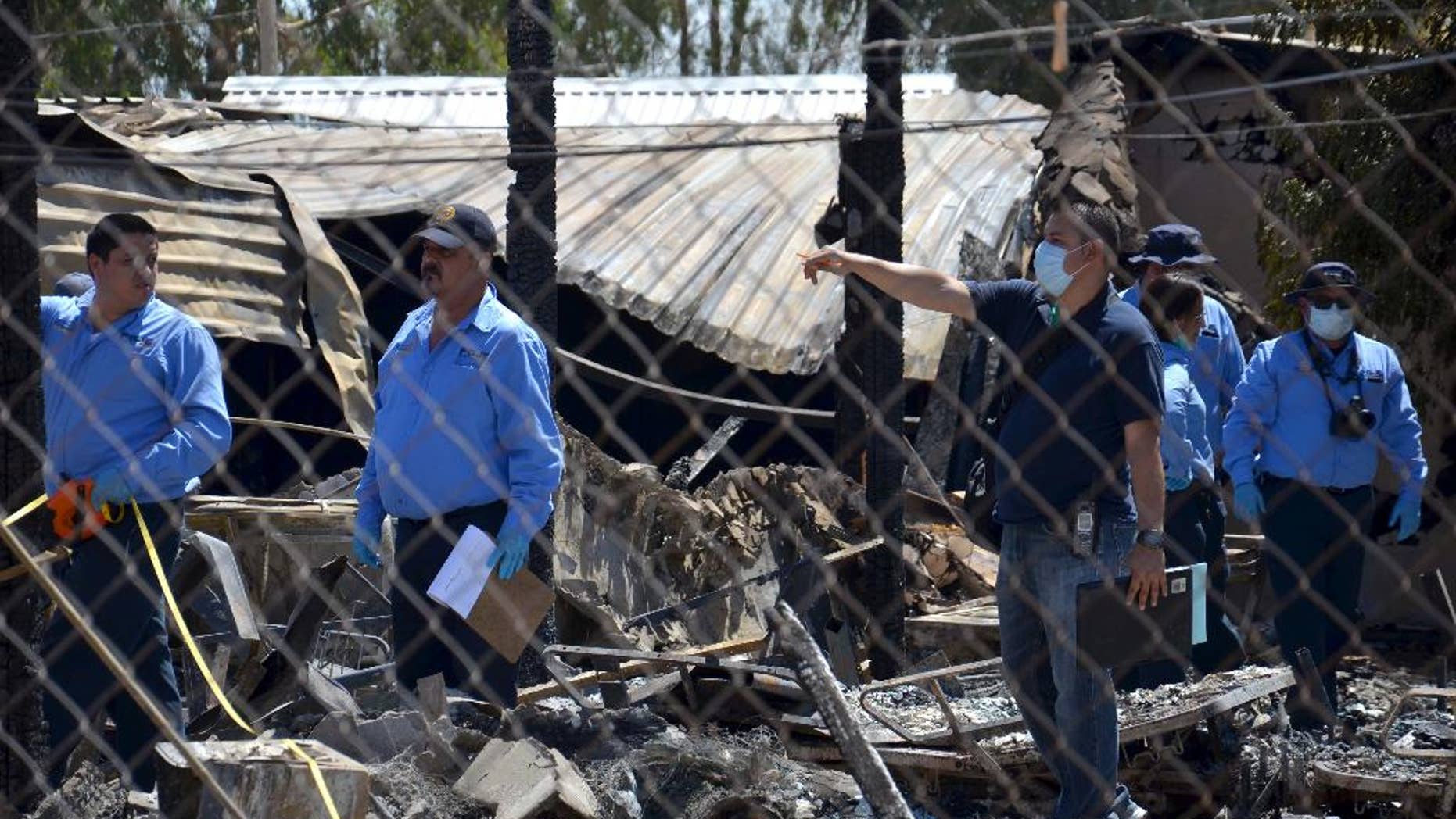Forensics work among the rubble of a nursing home after it caught fire in Mexicali, Mexico, Tuesday, June 23, 2015. The fire killed more than a dozen elderly residents at the home, and the cause of the blaze was being investigated by the state prosecutors' office, according to Mexicali Mayor Jaime Diaz Ochoa. (AP Photo/Cristian Torres)