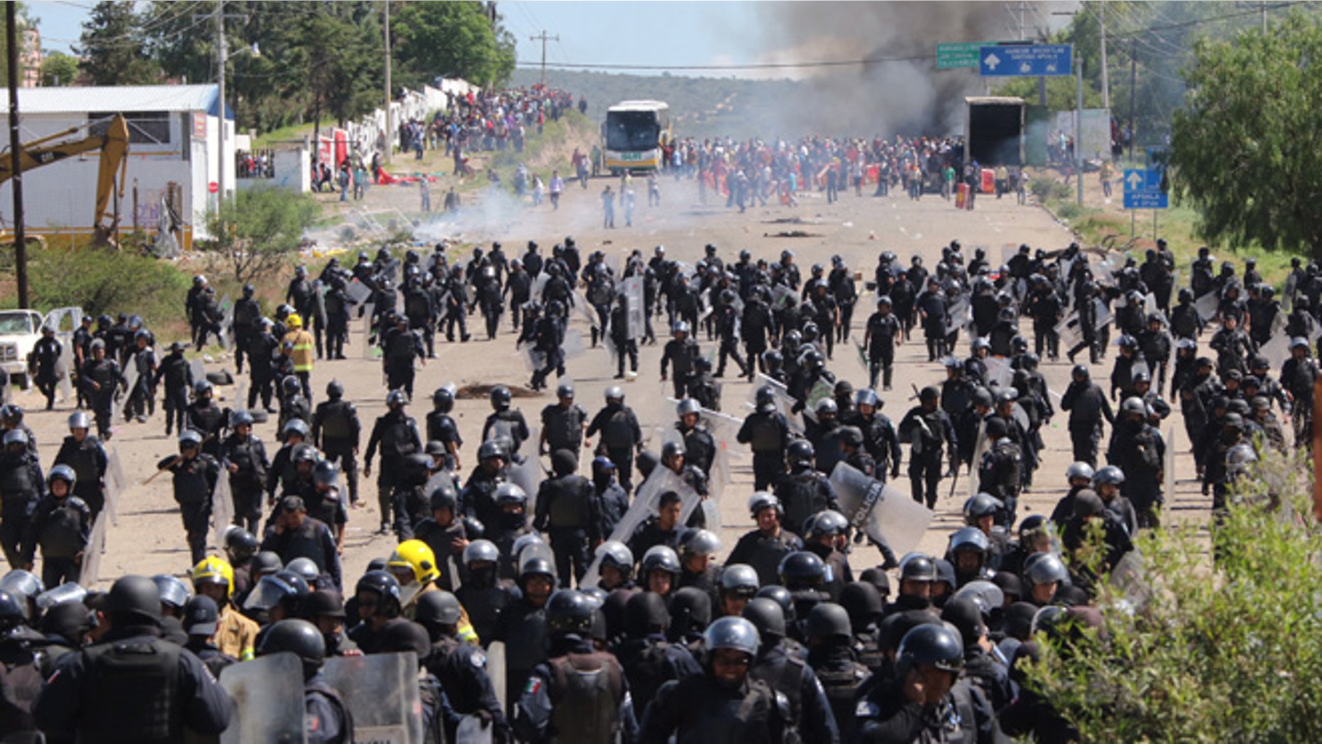 Riot police are forced to fall back as they battle with protesting teachers who were blocking a federal highway in the state of Oaxaca, near the town of Nochixtlan, Mexico, Sunday, June 19, 2016. The teachers are protesting against plans to overhaul the country's education system which include federally mandated teacher evaluations. (AP Photo/Luis Alberto Cruz Hernandez)