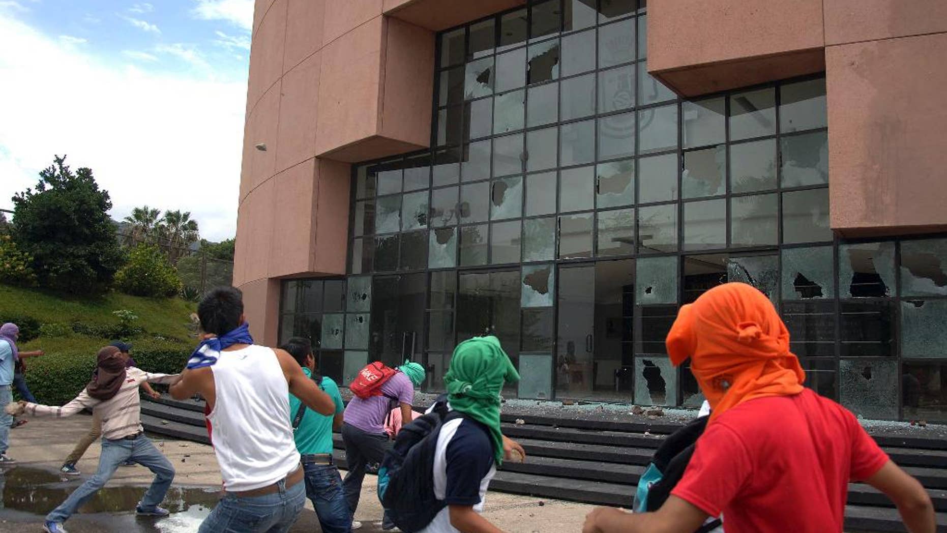 Students from a rural teachers college throw rocks at the entrance to the State Congress after marching through the streets of Chilpancingo, Mexico, Monday Sept. 29, 2014. The students were protesting after a violent weekend left at least 6 people dead and 57 students reported missing. State authorities have confirmed that 22 local policemen have been arrested following the deaths. (AP Photo/Alejandrino Gonzalez)