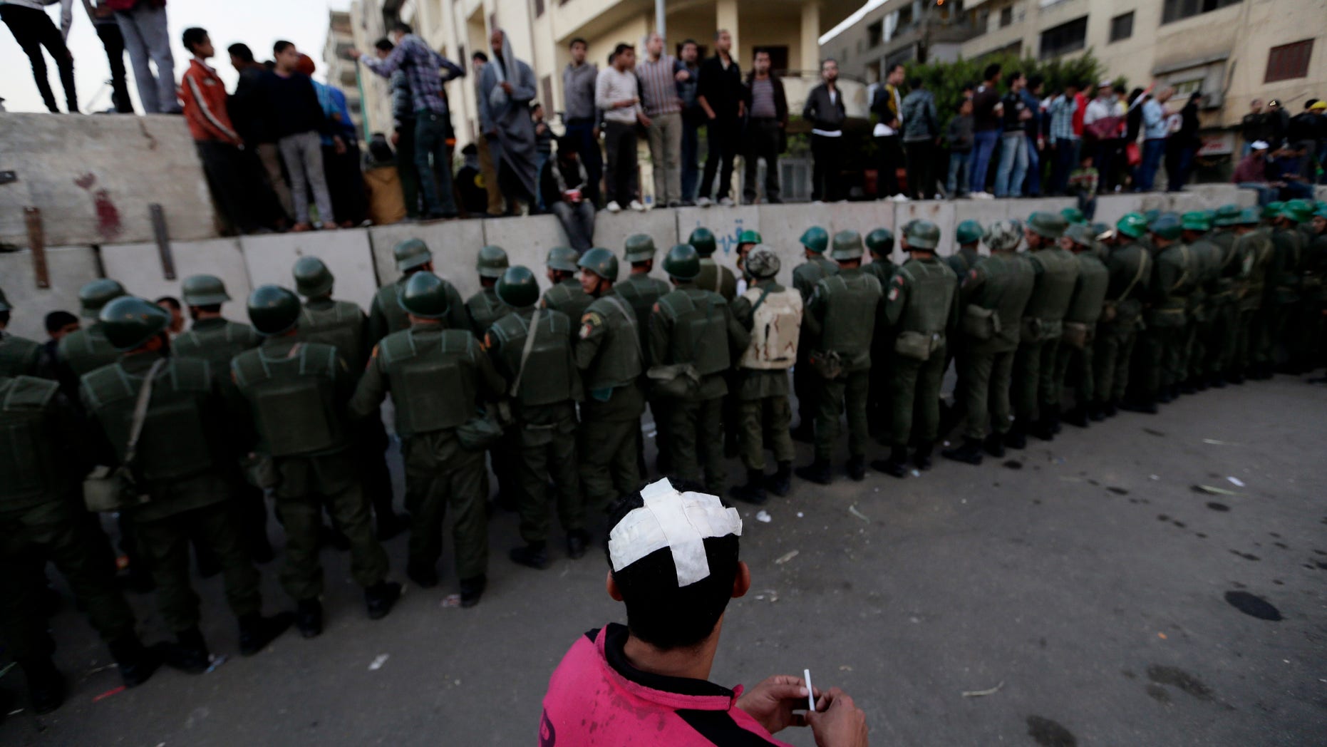 Dec. 9, 2012 - Egyptian army soldiers stand guard as protesters stand on top of cement blocks near the presidential palace in Cairo, Egypt.
