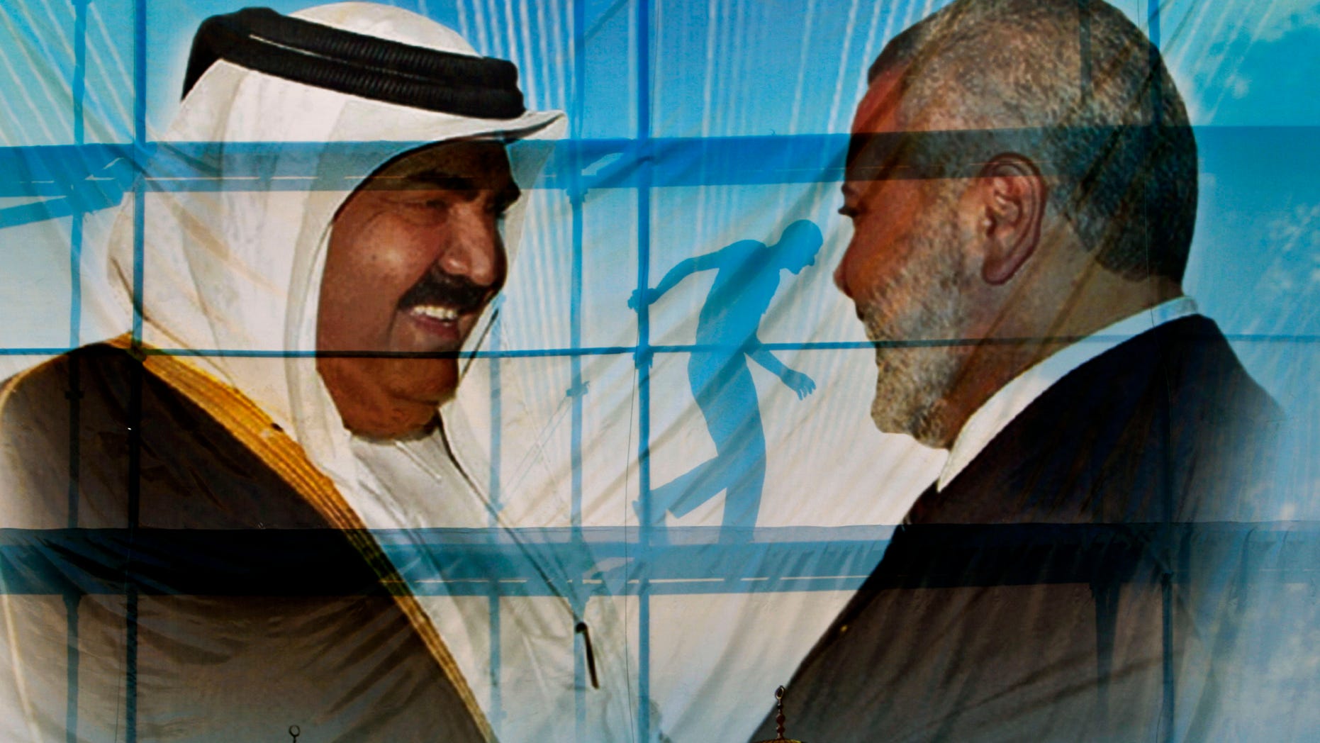 A Palestinian worker walks behind posters of the Emir of Qatar Sheikh Hamad bin Khalifa al-Thani, left, and Gaza's Hamas Prime Minister Ismail Haniyeh, right, in preparation for the visit to Gaza at Palestine stadium in Gaza City, Monday, Oct. 22, 2012.