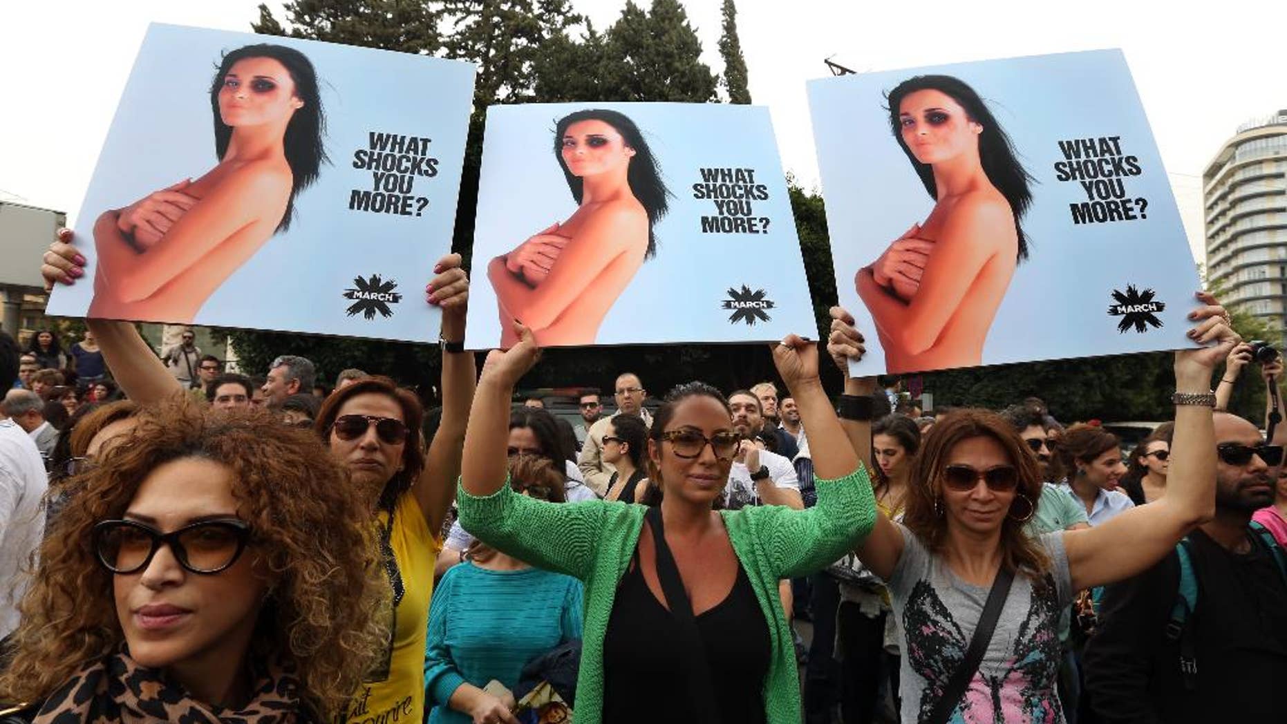 Lebanese women hold posters to mark International Woman's Day during a rally of thousands demanding that parliament approves a law that protects women from domestic violence, in Beirut, Lebanon, Saturday, March. 8, 2014. Although Lebanon appears very progressive on women rights compared to other countries in the Middle East, domestic violence remains an unspoken problem and the nation’s parliament has yet to vote on a bill protecting women’s rights nearly three years after it was approved by the Cabinet. (AP Photo/Bilal Hussein)