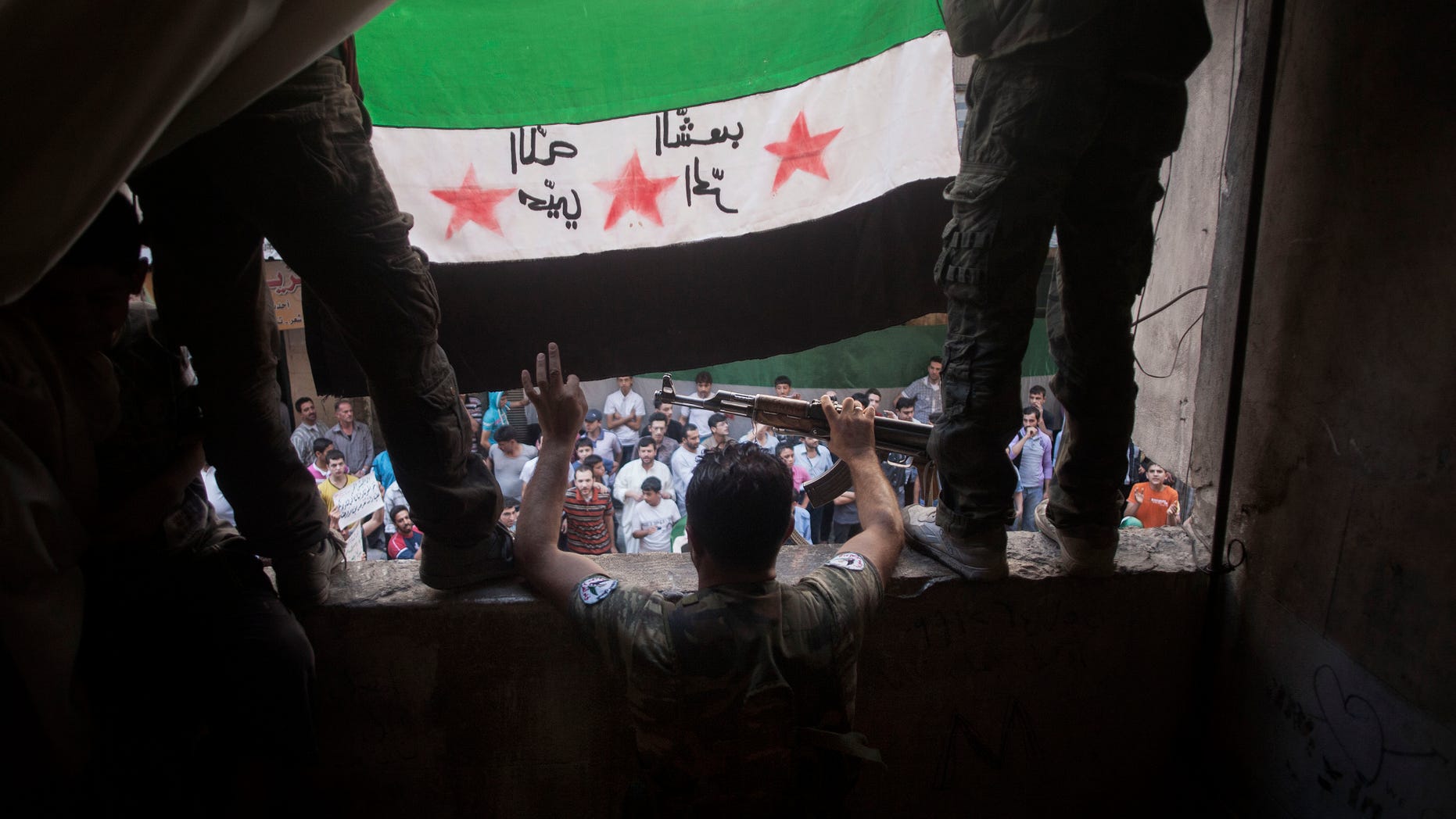 In this Friday, Sept. 21, 2012 photo, Free Syrian Army rebels hold a revolutionary flag on it during a demonstration in the Bustan al-Qasr neighborhood of Aleppo, Syria. The Britain-based Syrian Observatory for Human Rights said Friday that nearly 30,000 Syrians have been killed during the 18-month uprising against the Assad regime. Arabic on flag is reversed, but reads, "God welcome, free people." (AP Photo/ Manu Brabo)