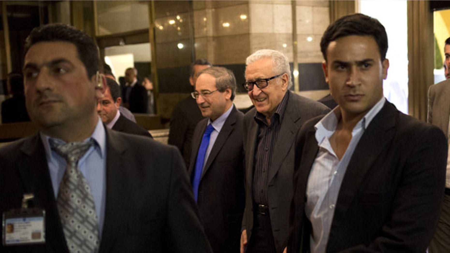 October 28, 2013: U.N.-Arab League envoy Lakhdar Brahimi, center right, and Deputy Syrian Foreign Minister Faisal Mekdad arrive to a hotel surrounded by security in Damascus, Syria. Brahimi is on his first trip to the country in almost a year. (AP Photo/Dusan Vranic)