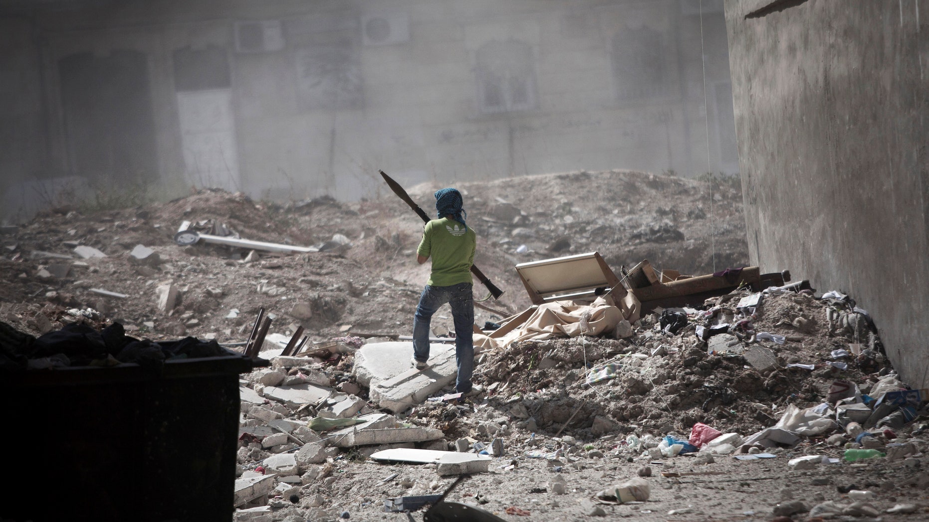 Sept. 26, 2012 - A Free Syrian Army fighter holds a rocket-propelled grenade launcher while taking cover after a tank blast in Aleppo, Syria.