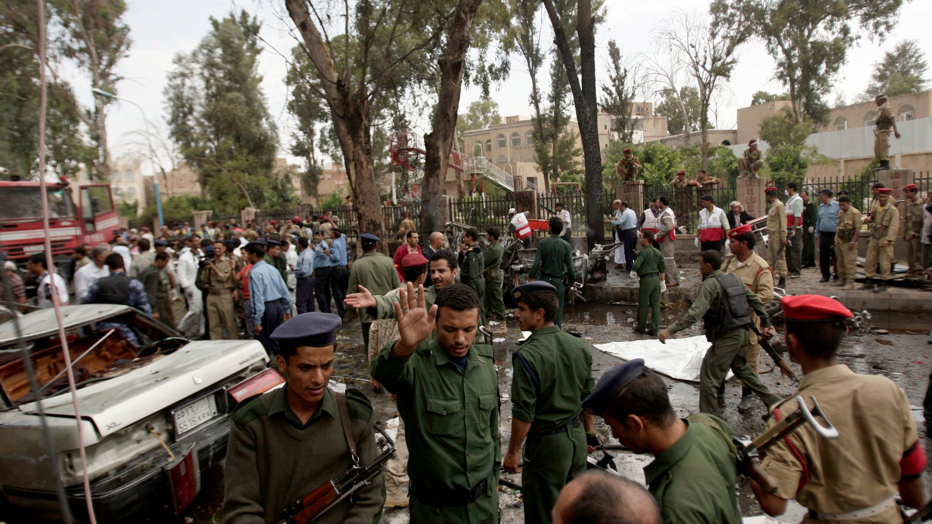 Yemeni officials and police gather at the site of a car bomb attack targeting the motorcade of the country's defense minister in Sanaa, Yemen, Tuesday, Sept. 11, 2012. Yemeni officials say a car bomb targeting the motorcade of the country's defense minister has killed several people, but the minister escaped unharmed. (AP Photo/Hani Mohammed)