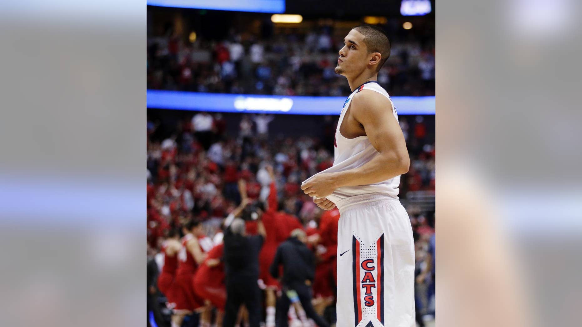 Arizona's Nick Johnson reacts as Wisconsin celebrates after overtime in a regional final NCAA college basketball tournament game, Saturday, March 29, 2014, in Anaheim, Calif. Wisconsin won 64-63 in overtime. (AP Photo/Jae C. Hong)
