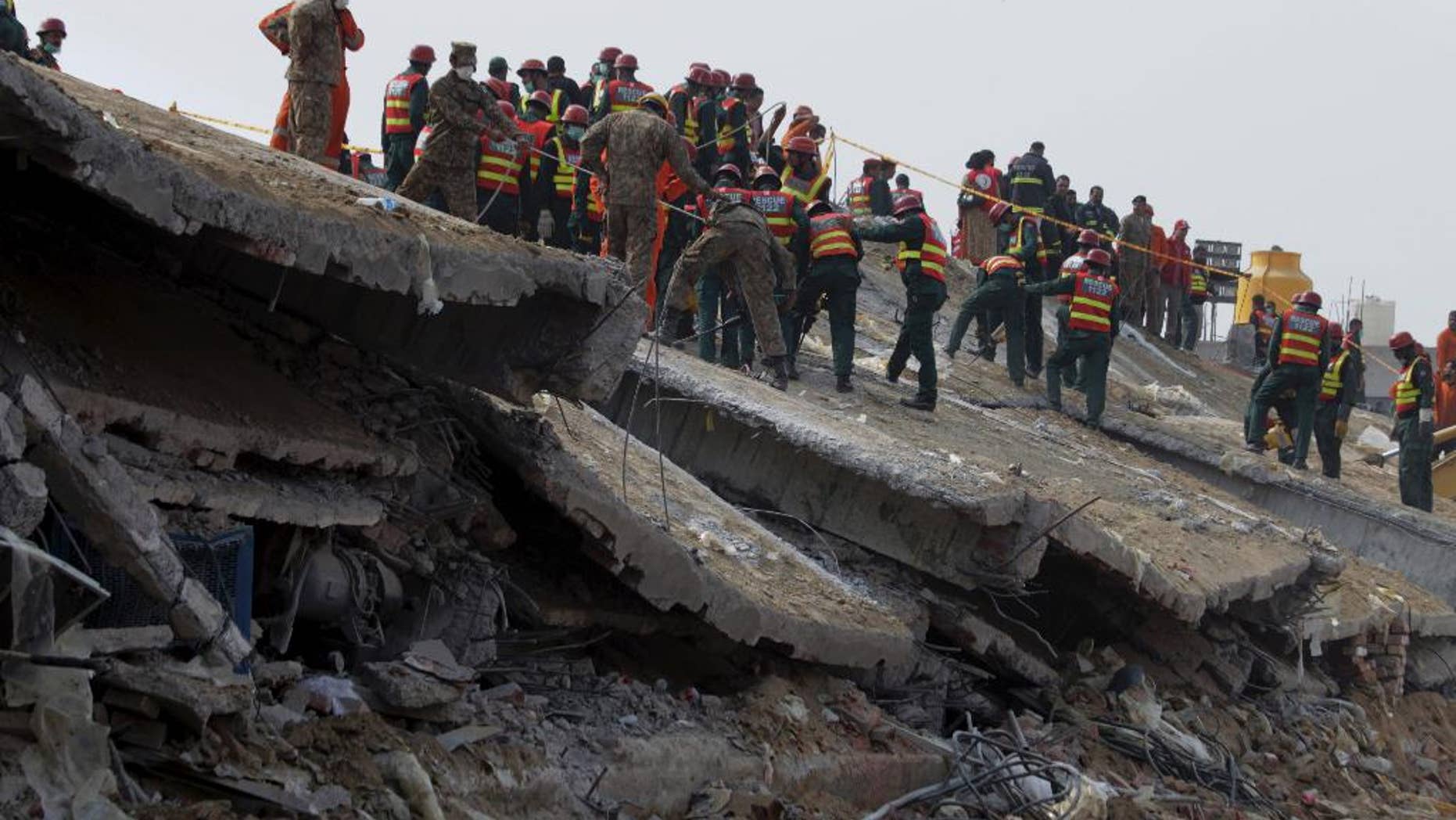 Pakistani army troops and rescue workers clear rubble of a collapsed building to recover bodies in Lahore, Pakistan, Saturday, Nov. 7, 2015. An official said rescue crews were carefully cutting steel and picking through concrete on Saturday to reach several workers believed to be still trapped. The building caved in just over a week after a magnitude-7.5 earthquake hit Pakistan, damaging nearly 75,000 homes. (AP Photo/K.M. Chaudary)