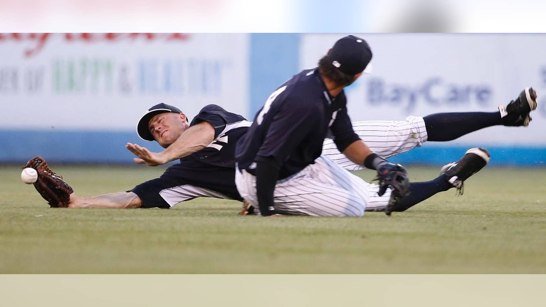 New York Yankees center fielder Brett Gardner loses the ball trying to catch a fly ball hit by Pittsburgh Pirates' Jordy Mercer while nearly colliding with Yankees second baseman Brian Roberts during the second inning of a spring exhibition baseball game against the Pittsburgh Pirates in Tampa, Fla., Friday, March 21, 2014. Mercer advanced to second on the play. (AP Photo/Kathy Willens)