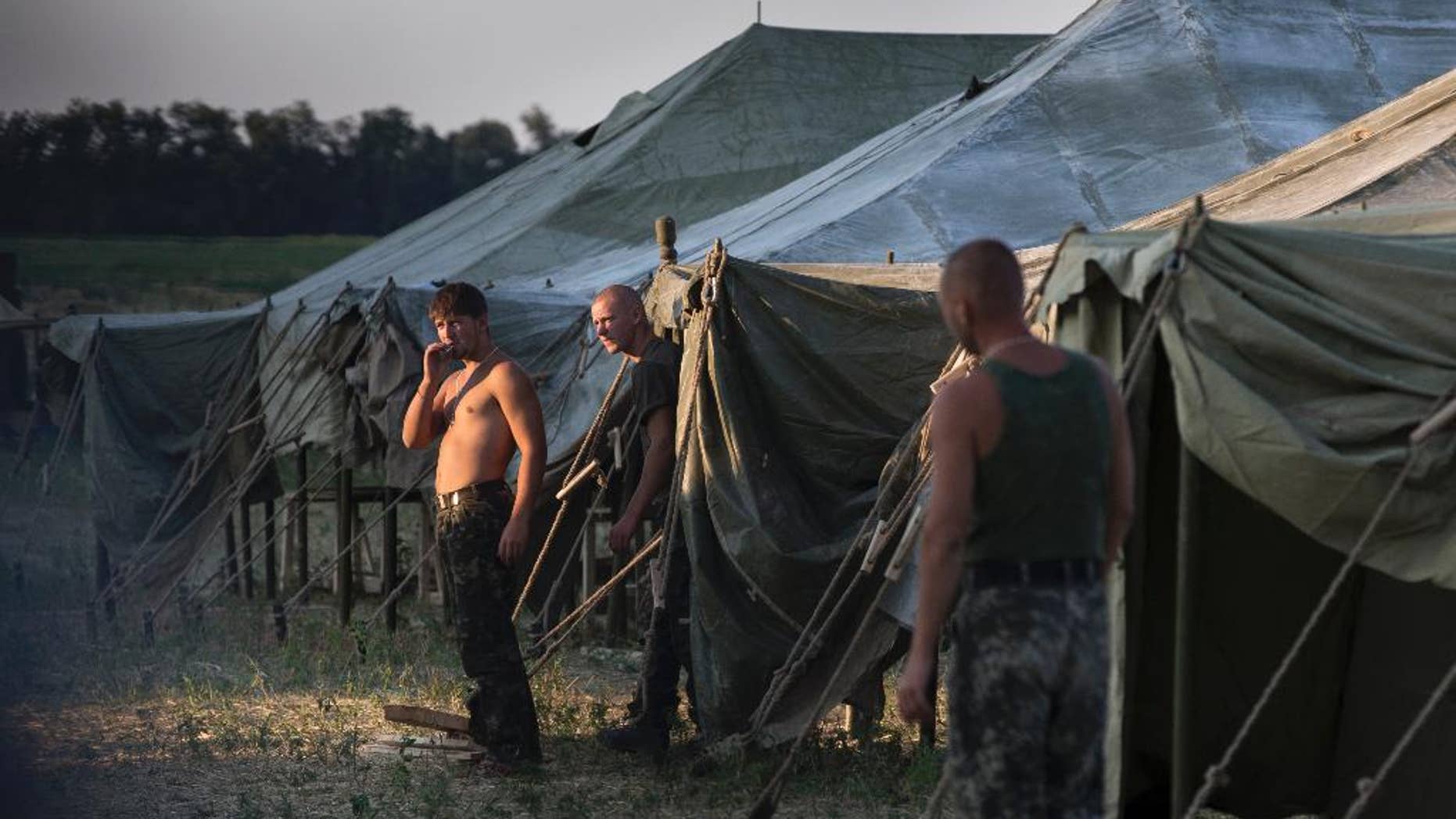 Ukrainian soldiers, who fled the conflict territory, spend their time at a tent camp as the sun sets over the scene near the Russia-Ukraine border just outside the village of Gukovo, Rostov-on-Don region, Southern Russia, Monday, Aug. 4, 2014. A Russian border security official said Monday that more than 400 Ukrainian soldiers have crossed into Russia. The Russian official said the soldiers deserted the Kiev government and the Russian side opened a safe corridor. (AP Photo/Alexander Zemlianichenko)