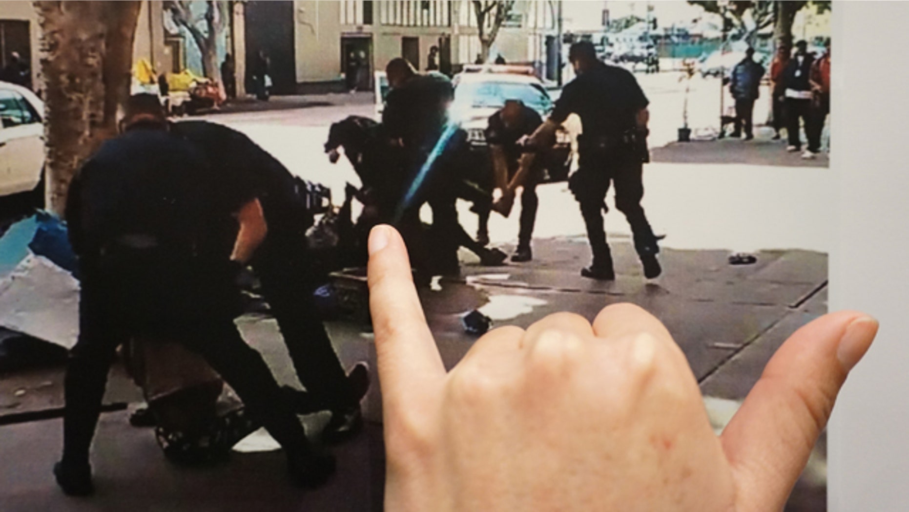 March 2, 2015: Los Angeles Police detective Meghan Aguilar points at photos released by police that could indicate evidence of a suspect holding a police officer's gun, seen in a video grab scene shot by a witness at the shooting of a homeless man on Skid Row of Los Angeles. (AP Photo/Damian Dovarganes)