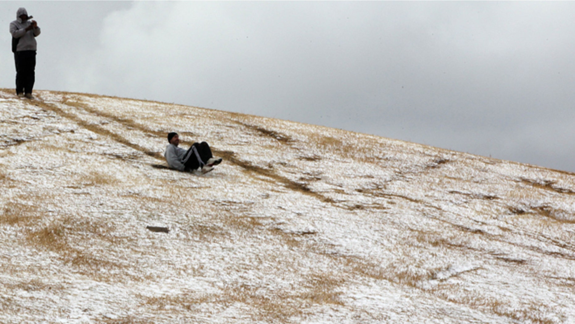 Aug. 7, 2012: A man slides down a hill after a rare snowfall in Johannesburg, South Africa.