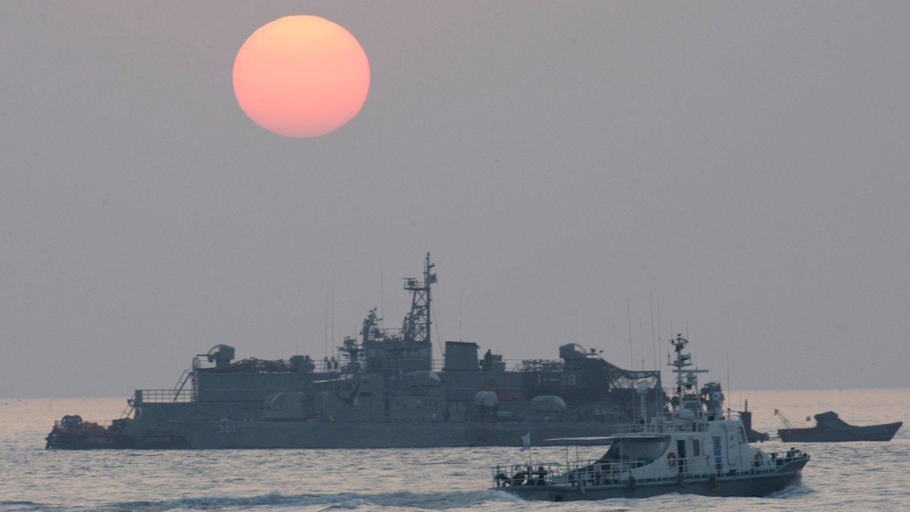 A government ship sails past the South Korean Navy's floating base as the sun rises near Yeonpyeong island, South Korea, Wednesday, Dec. 22, 2010.