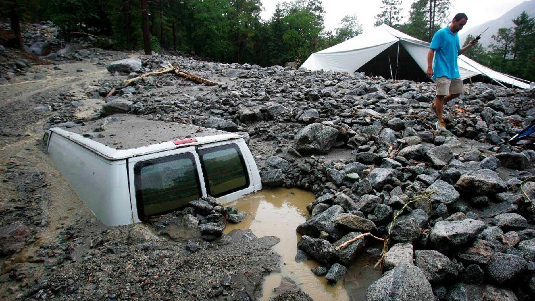 An official of Forest Home Christian Conference Center in Forest Falls, Calif., inspects damage on the property following thunderstorms on Sunday, Aug. 3, 2014. About 1,500 residents of Oak Glen, and another 1,000 residents of Forest Falls in the San Bernardino Mountains were unable to get out because the roads were covered with mud, rock and debris, authorities said. (AP Photo/The Press-Enterprise, David Bauman)