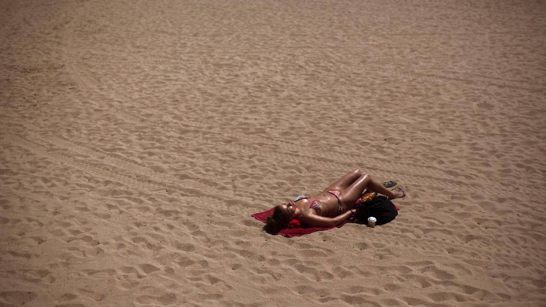 A woman sunbathes in a beach in Barcelona, Spain, Friday, May 15, 2015. The Iberian Peninsula has experienced record high temperatures for May as thermometers shot up to levels normally only seen in midsummer. (AP Photo/Emilio Morenatti)