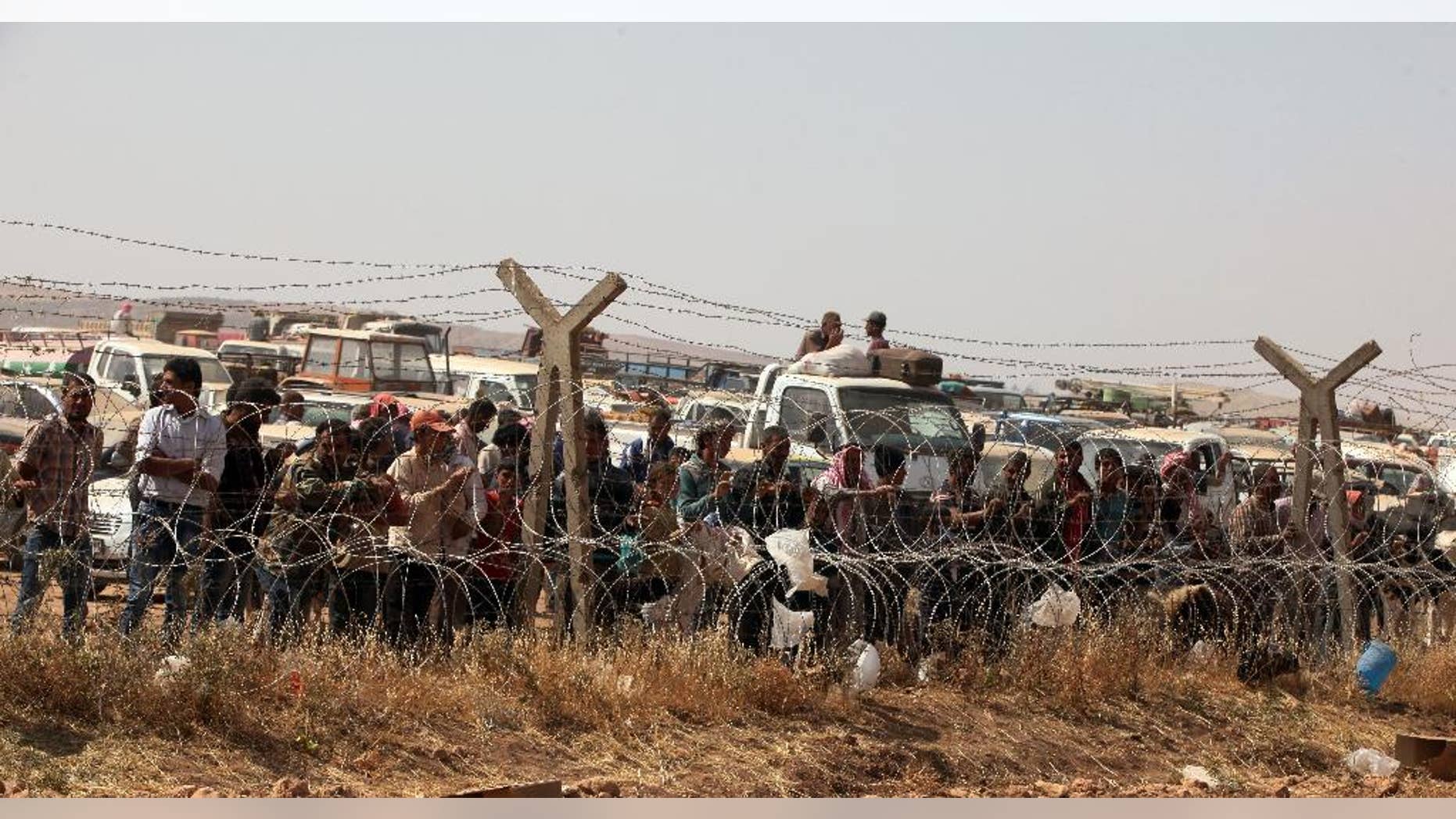 Syrian refugees wait for permission to enter Turkey at Yumurtalik crossing gate near Suruc, Turkey, Wednesday, Sept. 24, 2014. More than 200,000 people fleeing the Islamic State militants’ advance on Kobani, Syria, arrived in Turkey over the last five days to find safety. (AP Photo/Burhan Ozbilici)