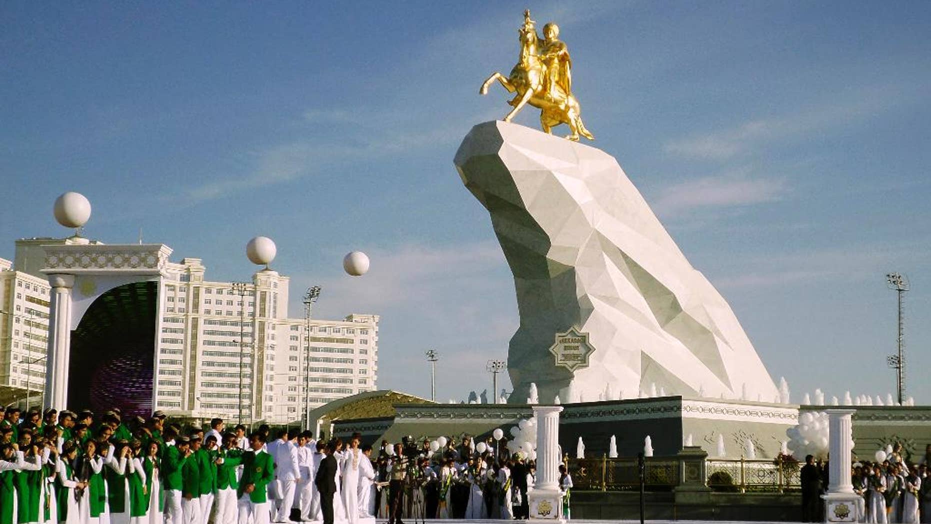 People gather for the monument unveiling ceremony in Ashgabat, Turkmenistan Monday, May 25, 2015. The isolated energy-rich Central Asian nation of Turkmenistan has unveiled a gold-leafed statue of the president in a gesture intended to burnish the leader's burgeoning cult of personality. The 21-meter monument presented to the public Monday consists of a statue of President Gurbanguly Berdymukhamedov atop a horse mounted on a towering pile of marble. (AP Photo/Alexander Vershinin)