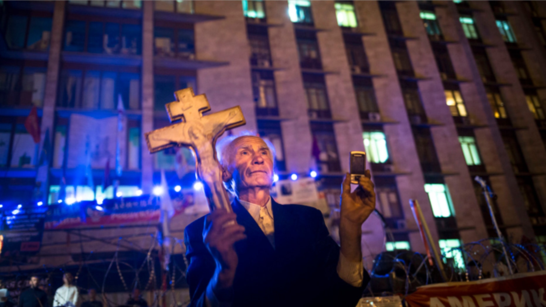 May 12, 2014: A pro-Russian man holds an Orthodox cross as a crowd celebrate declaring independence for Donetsk region at barricades in front of a regional administration building that was seized by pro-Russian activists. (AP Photo/Alexander Zemlianichenko)