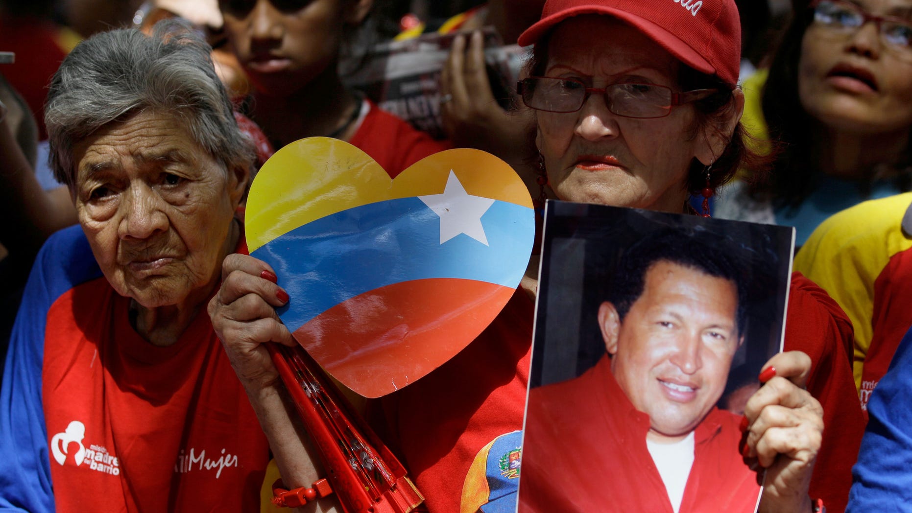 A woman holds a picture of Venezuela's President Hugo Chavez as supporters gather at Simon Bolivar square in Caracas,Venezuela, Sunday Dec. 9, 2012. Chavez is to return to Cuba Sunday for another surgery in his battle against cancer, which has led him to speak publicly of a successor for the first time. Chavez said Saturday that if there are "circumstances that prevent me from exercising the presidency further" Vice-President Nicolas Maduro should replace him for the remainder of his term.(AP Photo/Fernando Llano)