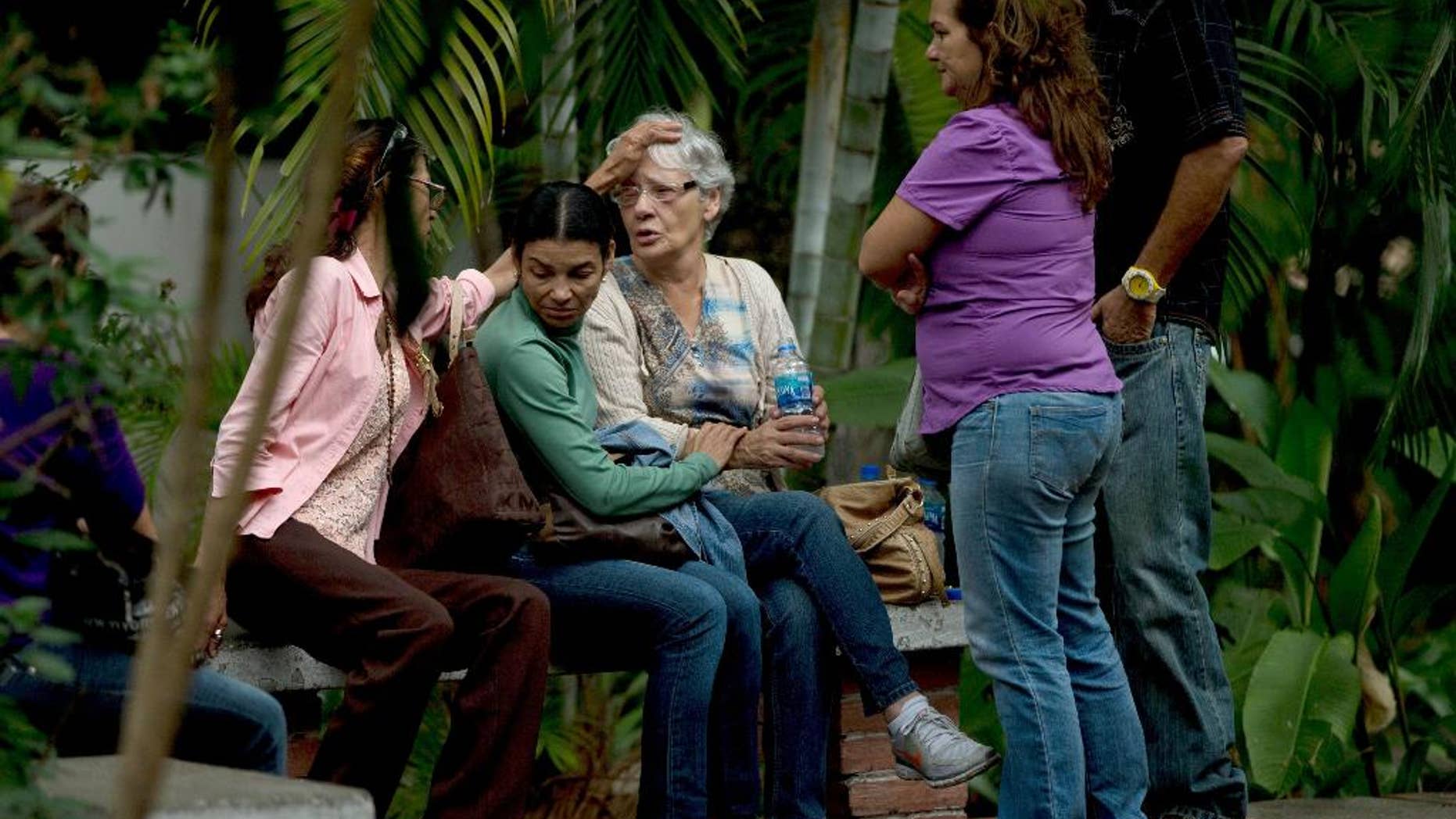 Josefa Alvarez de Gonzalez, center, is comforted by relatives of her husband, Rodolfo Gonzalez, outside the morgue office in Caracas, Venezuela, Friday, March 13, 2015. Rodolfo Gonzalez who was arrested last year during demonstrations against the Venezuela's President Nicolas Maduro government has died in state custody. The family of Gonzalez said that he died while being held at the headquarters of Venezuela's intelligence police. The 64-year-old pilot had been jailed since April 2014 and was awaiting trial on charges related to promoting violence during the protests. (AP Photo/Fernando Llano)