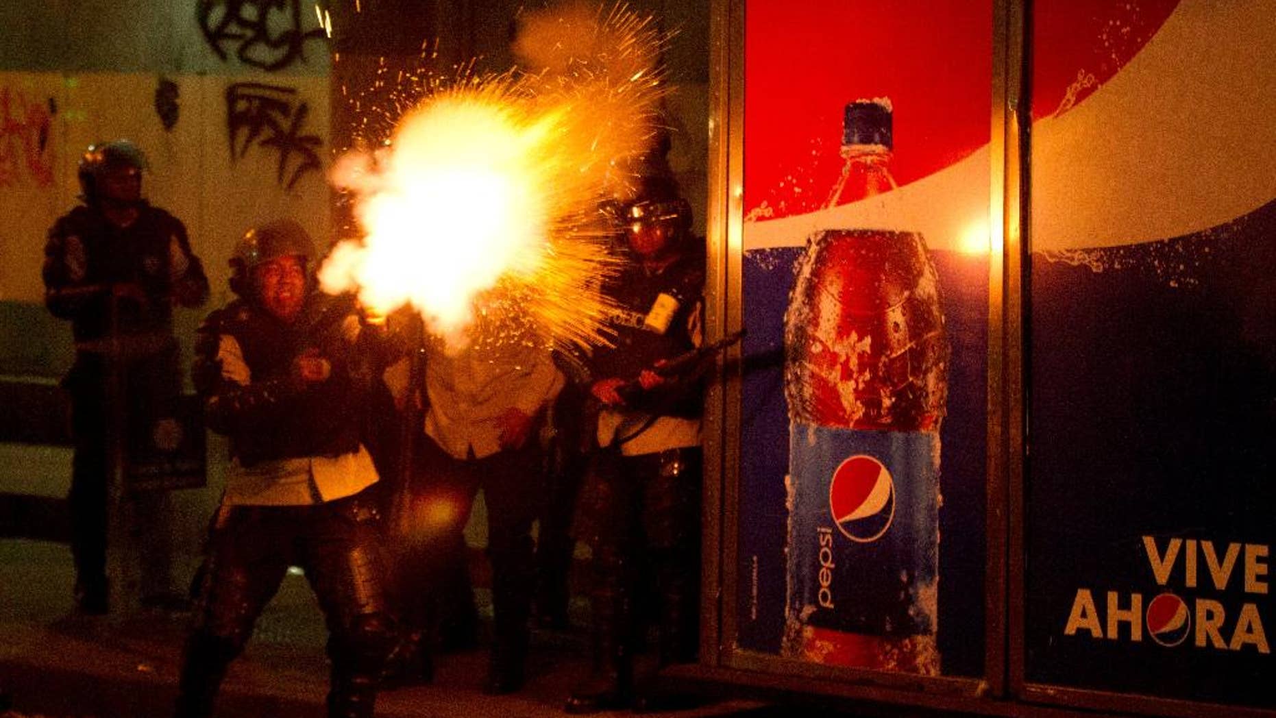 A Bolivarian National policeman fires tear gas at anti-government protesters during clashes in Caracas, Venezuela, Saturday, March 22, 2014. Two more people were reported dead in Venezuela as a result of anti-government protests even as supporters and opponents of President Nicolas Maduro took to the streets on Saturday in new shows of force. (AP Photo/Esteban Felix)