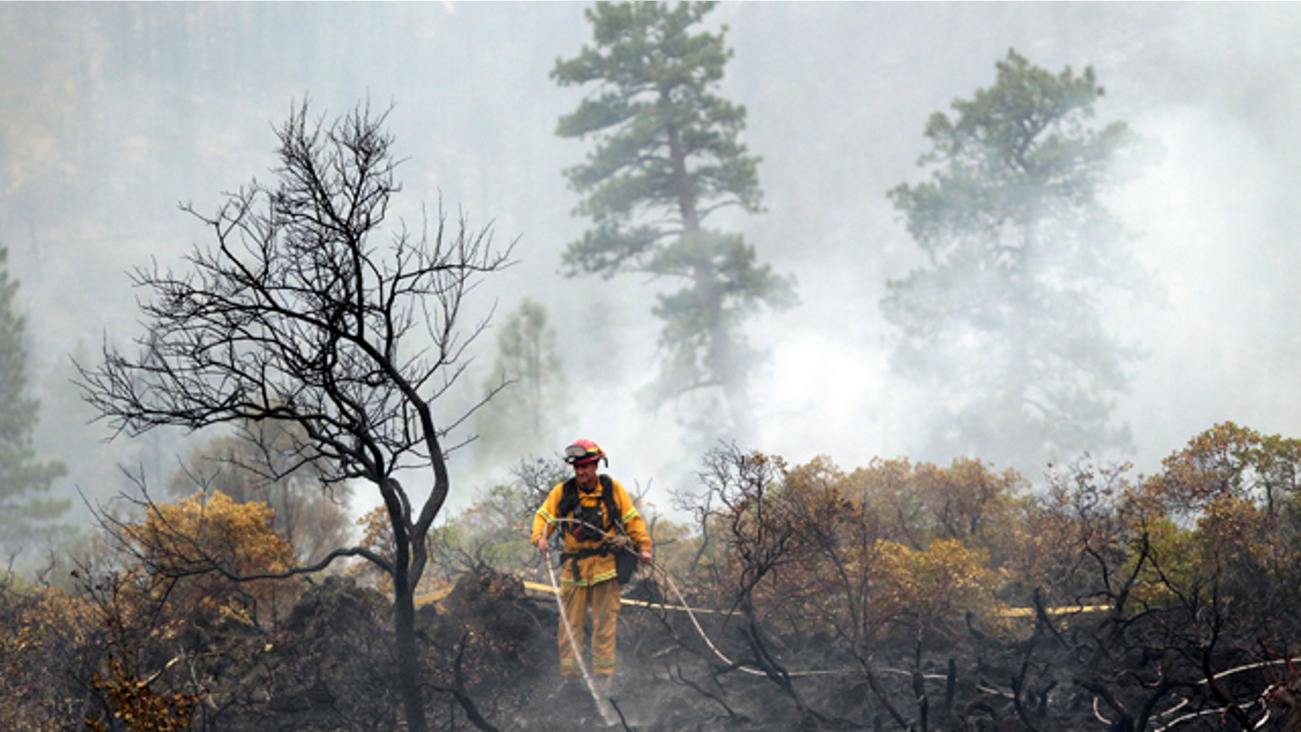 August 4, 2014: A firefighter with the Anderson, Calif., Fire Protection District douses hot spots left behind by the Eiler Fire along Highway 89 near Burney, Calif. (AP Photo/Marcio Jose Sanchez)