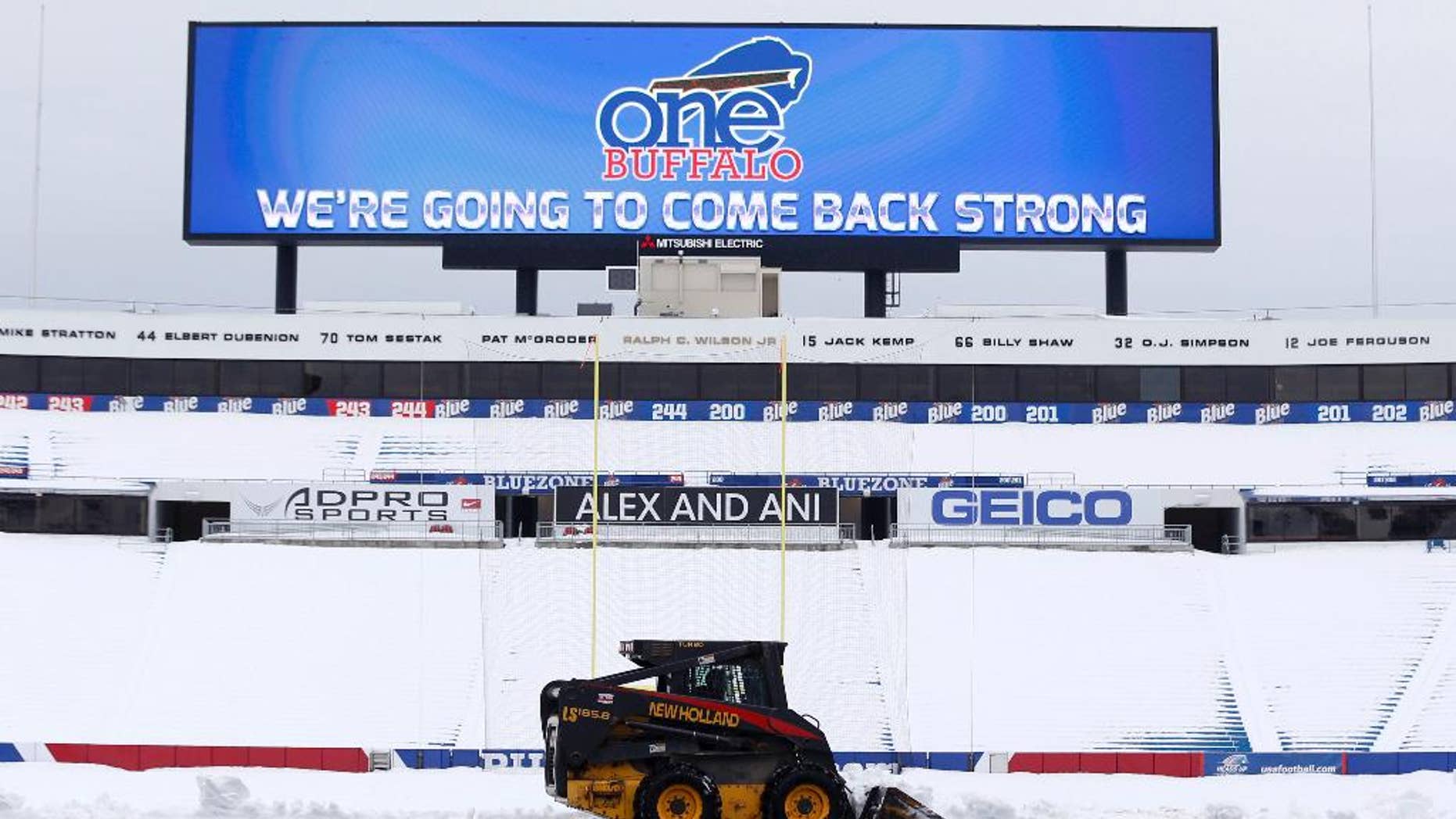 Workers clear snow from the field at Ralph Wilson Stadium on Sunday, Nov. 23, 2014, in Orchard Park, N.Y. Snowed out today at the stadium, the Bills are in Detroit to play their "home" NFL football game against the New York Jets on Monday night, Nov. 24, 2014. (AP Photo/Mike Groll)