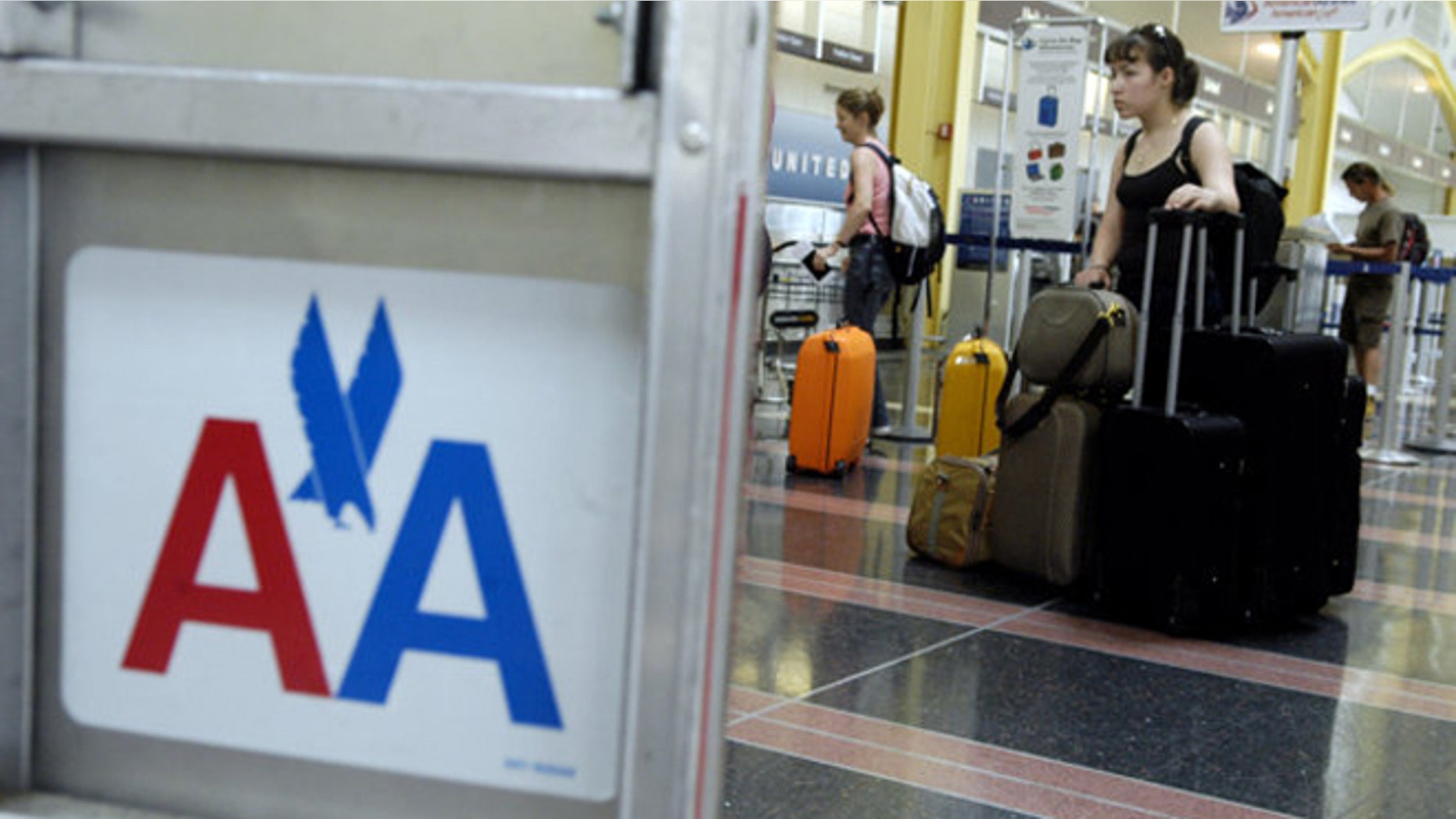A woman waits in line with luggage to check in for an American Airlines flight at Reagan National Airport in Arlington, Va.