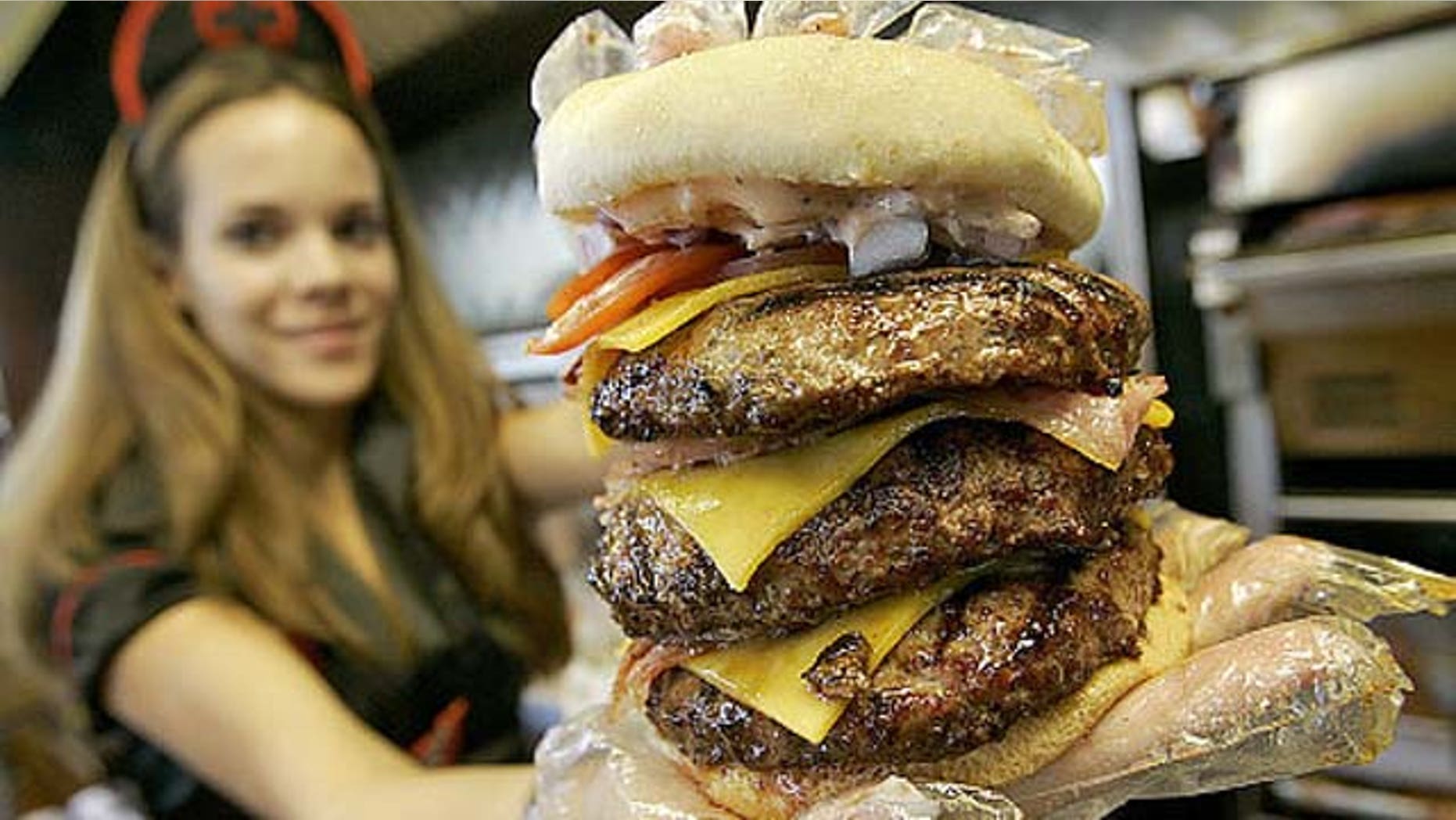 Courtney Chapman, a waitress dressed as a nurse at the Heart Attack Grill, holds up a triple bypass burger Friday, Dec. 1, 2006 in Tempe, Ariz.
