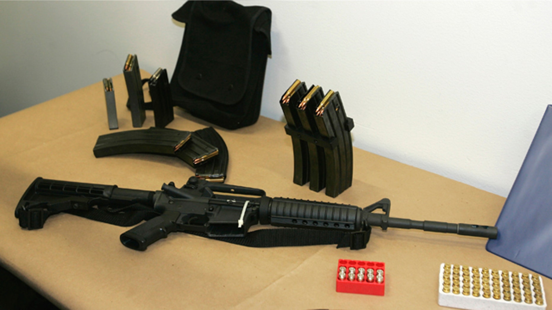 FILE - In this March 27, 2006 file photo, a Bushmaster AR-15 semi-automatic rifle and ammunition is seen at the Seattle Police headquarters in Seattle. In an effort to stem the illicit flow of weapons into Mexico, the Justice Department says gun shops in four Southwest border states will be required to alert the federal government to frequent buyers of high-powered rifles. (AP Photo/Ted S. Warren, File)