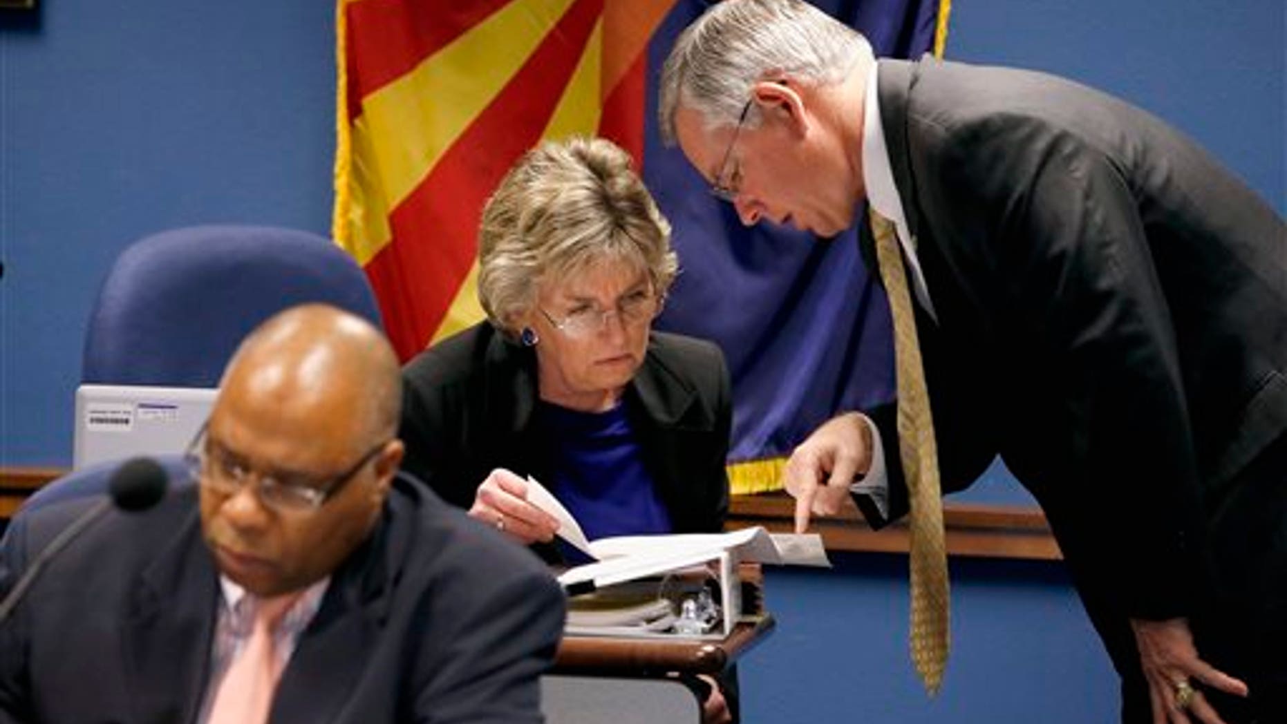 Maricopa County Attorney Bill Montgomery, right, talks with Arizona Legislature child protective services oversight committee co-chair Rep. Kate Brophy McGee, R-Phoenix, as Department of Economic Security Director Clarence Carter, left, refers to notes prior to a committee hearing at the Arizona Capitol Monday, Dec. 16, 2013, in Phoenix. The committee finds out an update on efforts to investigate more than 6,500 abuse and neglect reports that were not investigated by the Child Protective Services state agency in recent years. (AP Photo/Ross D. Franklin)