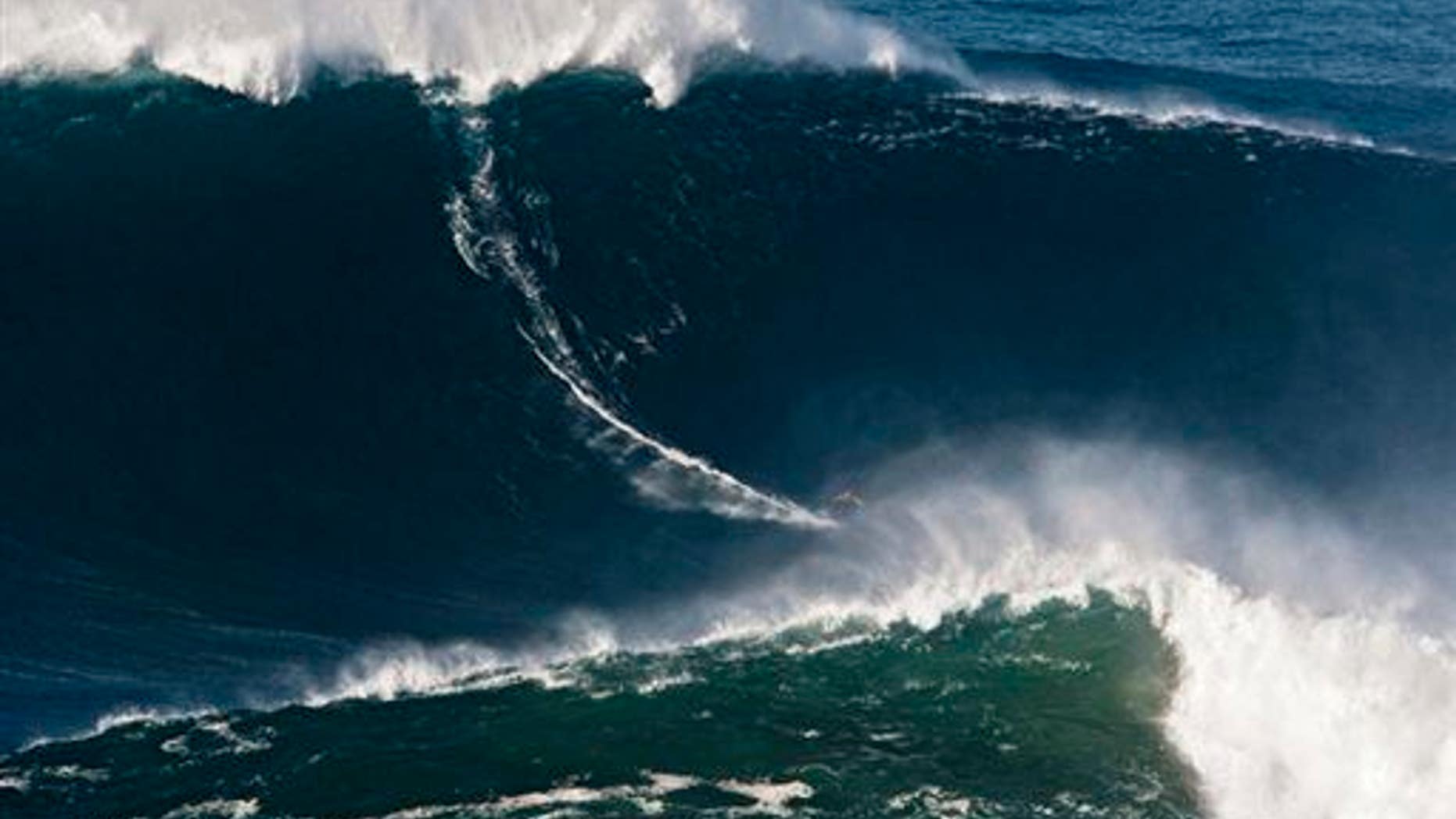 In this Nov. 1, 2011, file photo released by Nazare Qualifica/Polvo Concept, Garrett McNamara of Hawaii surfs what is being called the tallest wave ever ridden at Praia do Norte beach in Portugal. At 78 feet (24 meters), it's been certified by Guinness World Records.