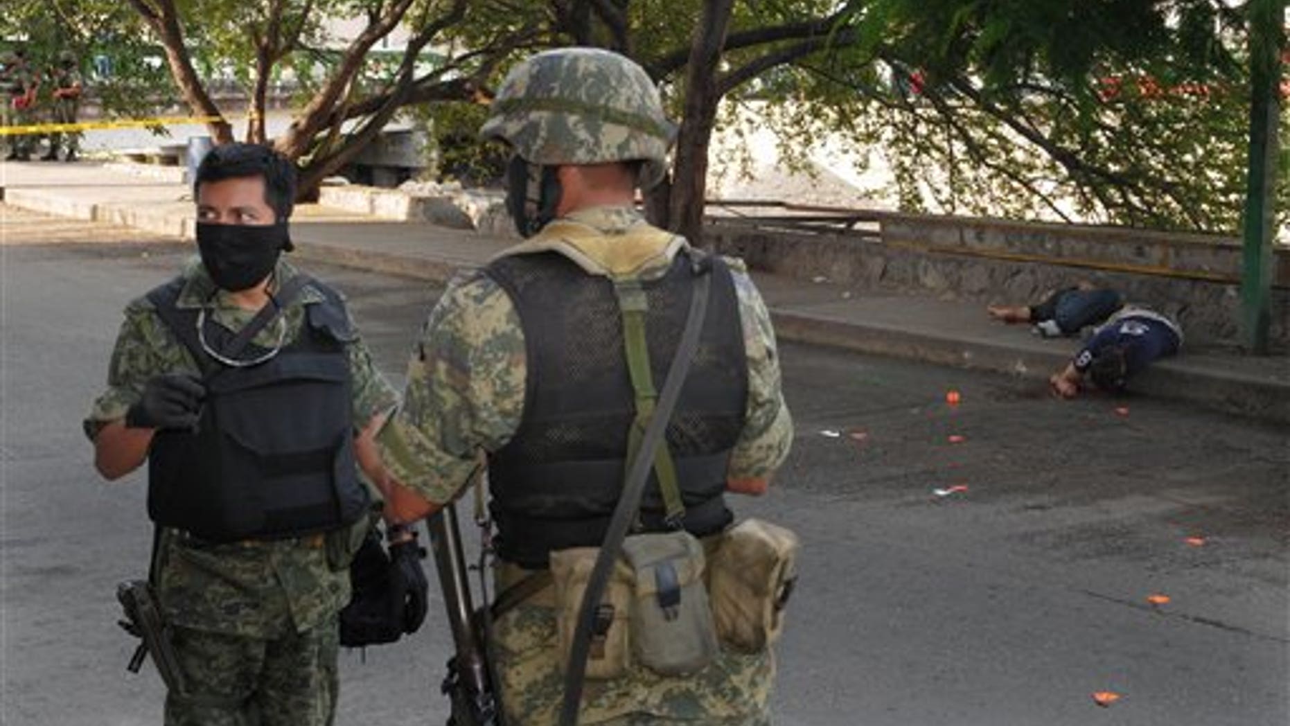 Jan. 8, 2011: Soldiers stand near the bodies of two men lying on the sidewalk after they were killed by gunmen in Acapulco, Mexico.