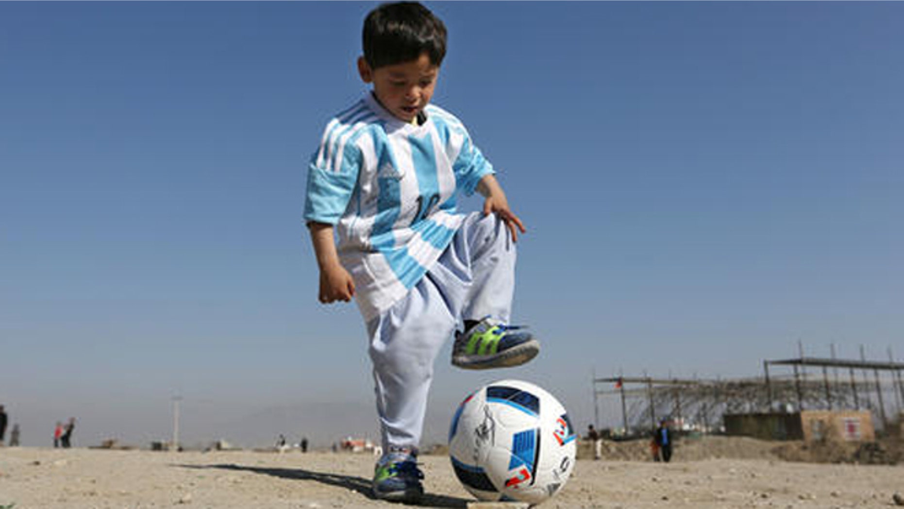 Murtaza Ahmadi, a five-year-old Afghan Lionel Messi fan plays with a soccer ball during a photo opportunity as he wears a shirt signed by Messi, in Kabul, Afghanistan, Friday, Feb. 26, 2016. Mohammad Arif Ahmadi, the father of the boy who was pictured wearing a homemade Argentina shirt with No. 10 on the back, said Friday they want to thank Messi, a UNICEF goodwill ambassador, in person.(AP Photo/Rahmat Gul)