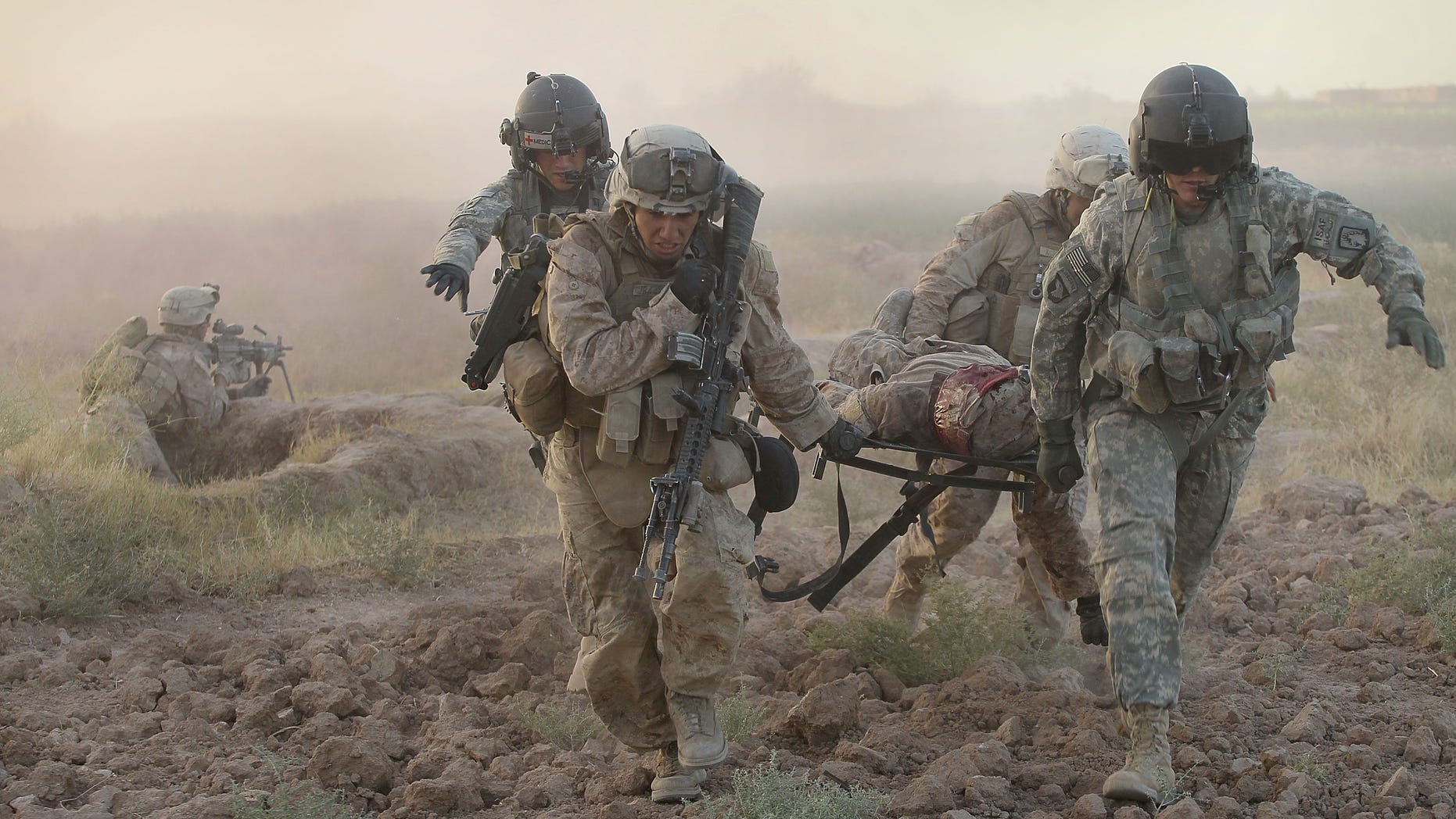 MARJA, AFGHANISTAN - SEPTEMBER 23: Army MEDEVAC helicopter crew members with Dustoff Task Force Shadow of the 101st Combat Aviation Brigade help Marines carry a severely wounded Marine to a helicopter on September 23, 2010 near Marja, Afghanistan. The Marine later died of his injuries. (Photo by Scott Olson/Getty Images)